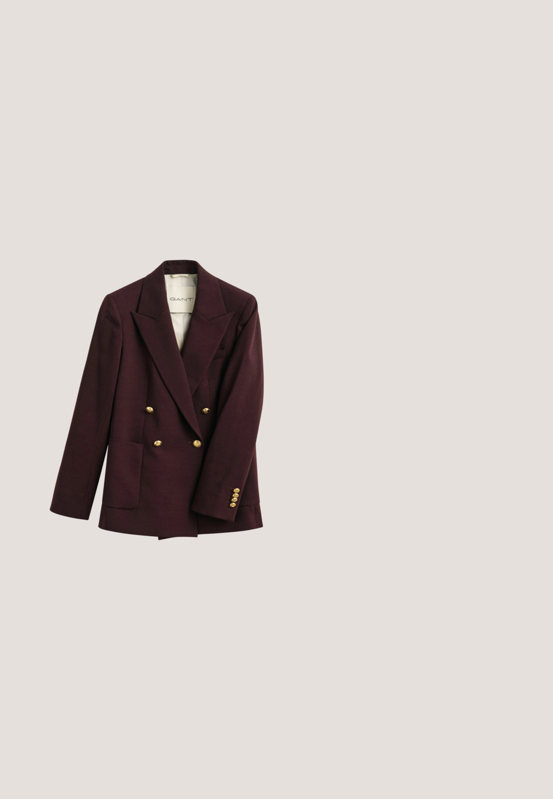 Donkerpaarse dubbelgeknoopte blazer met brede revers en gouden knopen voor en aan de manchetten, met een zak aan de onderkant links.; Crème kabelgebreide mouwloze trui met een V-hals en ribbelzoom. Beschikt over een textuurpatroon en een logo-label op de hals.; Witte blouse met lange mouwen, knoopsluiting en een button-down kraag, weergegeven op een witte achtergrond.; Plissé midi-rok in diep rood, met een gestructureerde stof en gelijkmatig verdeelde verticale plooien. De zoom valt rond de middenkuit.; Bruine leren loafers met een ronde neus, strikdetail en sierstiksels langs de wreef. Platte zwarte rubberen zool.; Bruine leren handtas met een gestructureerd ontwerp, bovenhandvatten, een gouden sluiting en zichtbare stikseldetails voor textuur.