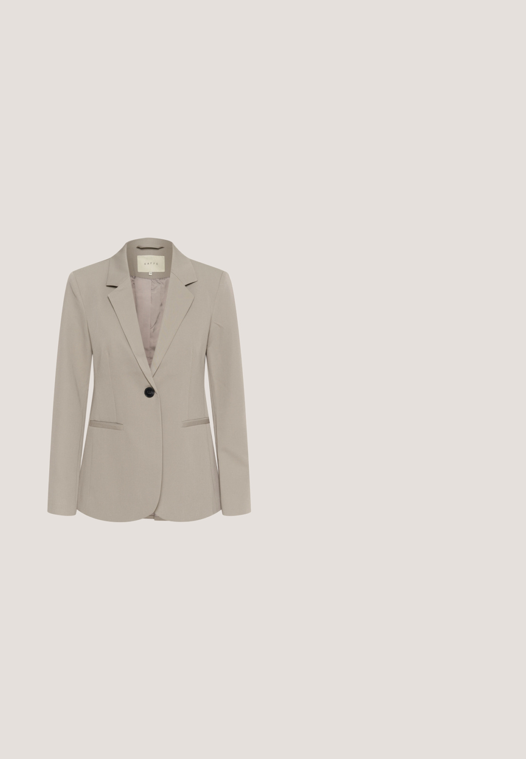 Lichte beige blazer gemaakt van soepele stof met een notch-kraag, één zwarte knoop en twee voorzakken. Gevoerd met een zachter beige materiaal.; Effen beige T-shirt met korte mouwen en ronde hals, met een klein label "soaked" aan de binnenkant van de nek, weergegeven tegen een witte achtergrond.; Beige op maat gemaakte broeken met een hoge taille, geplooide voorkant en taps toelopende pijpen. De stof lijkt glad met een subtiele glans. Geen zichtbare zakken.; Suède sneakers in lichtbruin met crèmekleurige accenten, voorzien van een gestructureerd zijpaneel, platte veters en een rubberen zool.; Kleine beige leren bucketbag met een enkele lange hengsel en een gladde, licht gestructureerde oppervlak.; Goudkleurige open ring met een abstracte, onregelmatige gehamerde textuur en glanzend, reflecterend oppervlak.