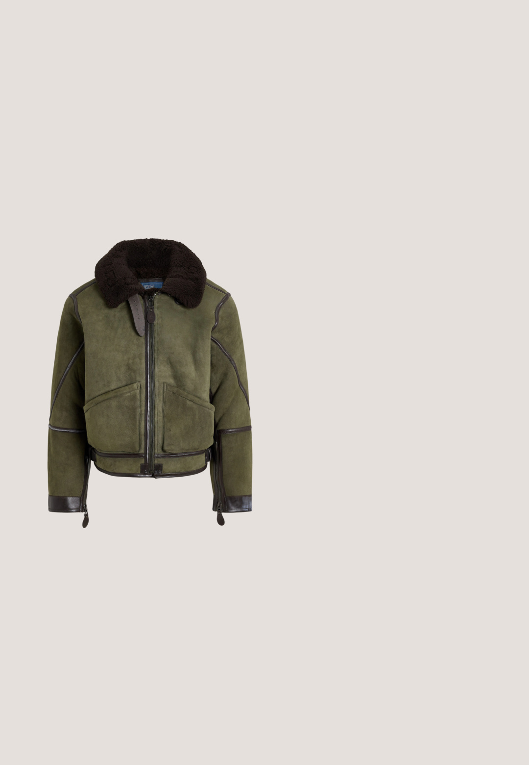 Bomberjack in olijfgroen suède met grote zwarte shearlingkraag, rits aan de voorkant, twee zakken en leren biezen aan de randen en mouwen.; Beige kabelgebreide trui met ronde hals, lange mouwen en klein blauw Polo Ralph Lauren-logo op de linkerborst.; Witte T-shirt met ronde hals met een afbeelding van een beer in een smoking naast een bruine paard, met daaronder de tekst Polo Bear by Ralph Lauren.; Bruine, recht gesneden broek met riemlussen, knoop en rits aan de voorkant, en zijzakken op een witte achtergrond.; Bruine suède enkellaars met veter aan de voorkant, stikseldetails, hieltreklus en witte geribbelde zool op een effen achtergrond.; Zwarte Polo Ralph Lauren leren toilettas met voorvak met rits en zijhandvat.