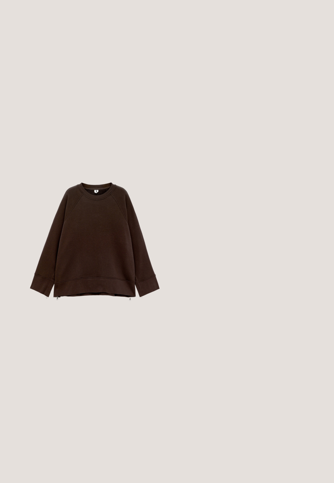 Sweatshirt long à manches longues marron foncé avec un col rond, des épaules tombantes, des poignets larges et de petites fermetures éclair sur les côtés à l'ourlet.; Chemise marron courte à boutons avec manches longues, poignets élastiques, col pointu et poche poitrine sur fond blanc.; Pantalon crème à taille haute et jambes larges, avec bouton avant, fermeture éclair, passants pour ceinture et poches latérales inclinées.; Baskets en daim marron avec surpiqûres décoratives blanches, semelle en caoutchouc plate et fermeture à lacets, présentées de profil sur fond uni.; Sac fourre-tout en daim marron avec des anses en cuir foncé et une petite étiquette en cuir attachée sur un fond clair uni.; Bague en métal doré avec un design abstrait épais, ondulé et une bande ajustable ouverte.
