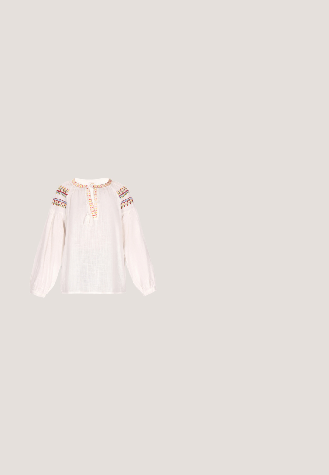 Witte blouse van een lichte, gestructureerde stof. Beschikt over een ronde halslijn, elastische lange mouwen en kleurrijke geborduurde accenten op de schouders.; Roeskleurige, middellange rok met een elastische tailleband en zachte, vloeiende stof voor comfort. Geen zichtbare patronen of accenten.; Beige suède enkellaars met een ronde neus en een bovenwerk met franjes. Voorzien van een blokhak van gemiddelde hoogte en een stevig ontwerp met een lusdetail aan de achterkant.; Bruine suède crossbodytas met gouden oogjes op de verstelbare riem, franjes aan de zijkanten en klein gouden RLL-logo op de voorflap.; Zilveren halsketting met drie gelaagde kettingen. De langste ketting heeft een getextureerde ronde hanger, terwijl daarboven een gladde schijfhanger is.; Geweven bruine leren riem met een ronde gouden gesp, met een gevlochten textuur en een gladde afwerking aan de binnenzijde.