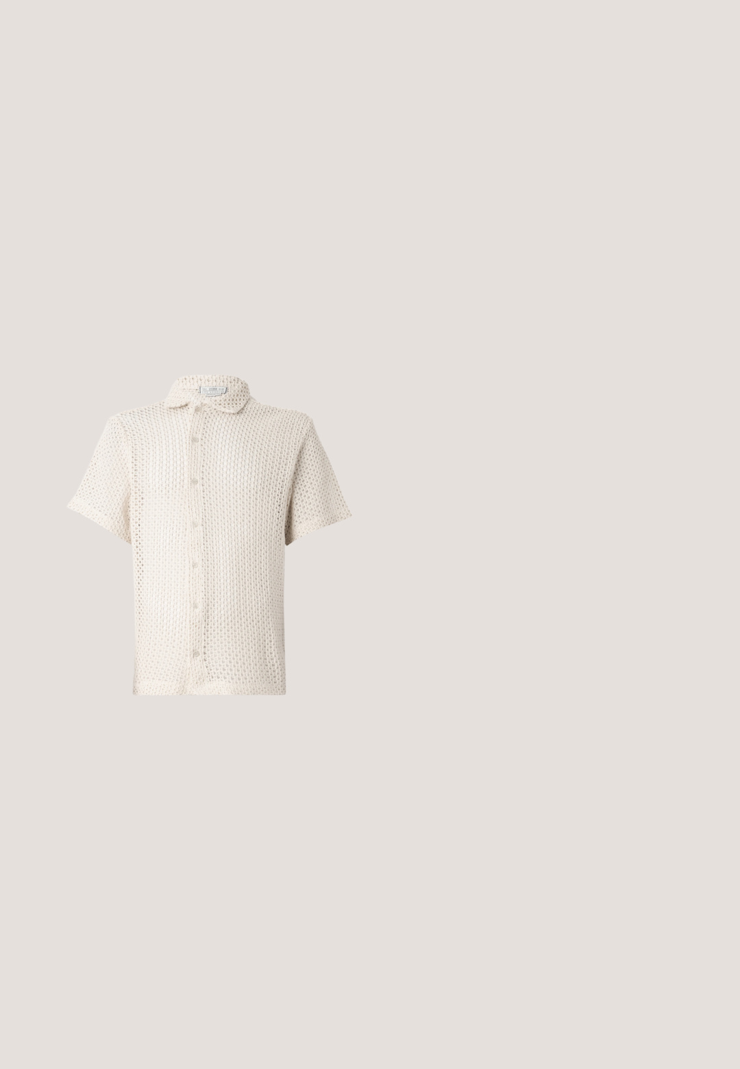 Camisa de botones de manga corta, color beige claro, hecha de un tejido texturizado y de punto abierto, con cuello y cinco botones en el frente.; Pantalones de pierna ancha en verde claro, hechos de una tela suave y texturada. Incluye un cierre de botón frontal y cinco bolsillos.; Sandalia tipo chancla negra de Calvin Klein descansando sobre una alfombra beige junto a una mesa redonda de color ámbar, con un fondo de pared revestida de madera.; Gafas de sol cuadradas de color marrón oscuro con monturas gruesas y patillas ligeramente inclinadas, apoyadas sobre una superficie gris clara.; Bolsa tote de lona negra con dos correas para el hombro y un diseño circular en relieve sutil en el frente.; Cinturón de cuero negro con acabado mate, que presenta una hebilla metálica rectangular y una correa que muestra el logo de Calvin Klein.