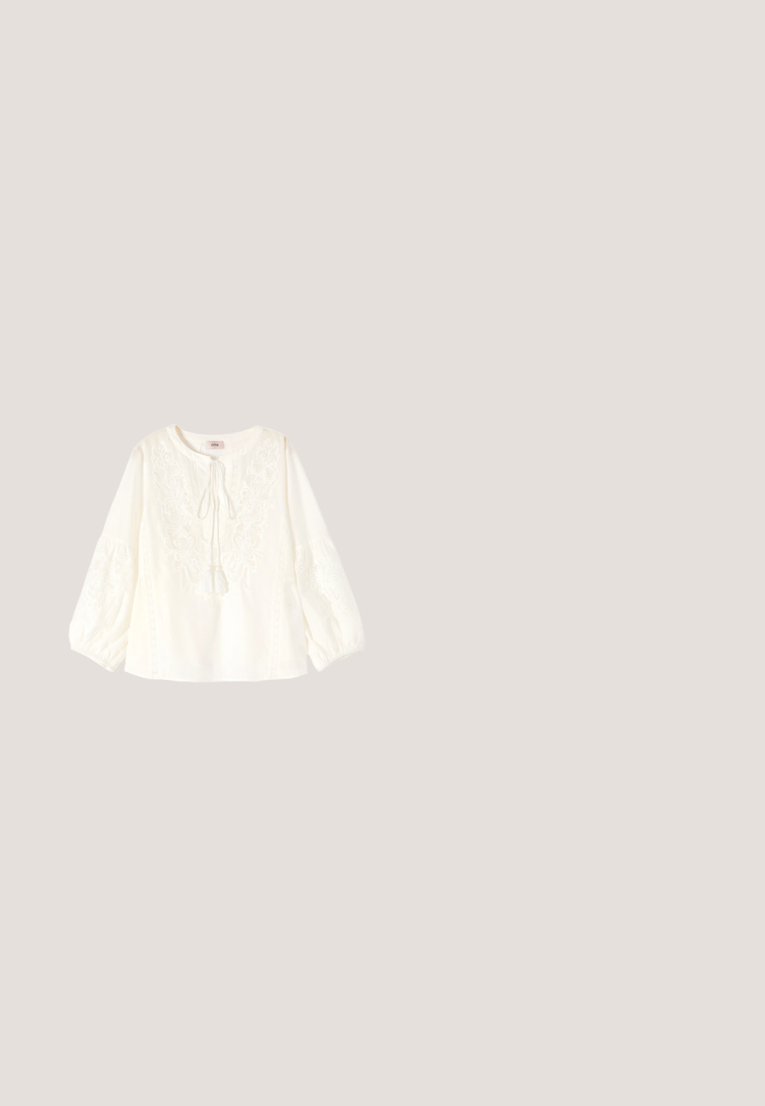 Witte blouse met lange mouwen met bloemenborduursel, kwastjesstrik bij ronde halslijn en elastische manchetten.; Roze midirok met kleine oranje en groene bloemenprint en kanten rand aan de zoom, rechte pasvorm en elastische tailleband.; Bruine leren enkellaars met een gladde afwerking, elastische zijpanelen, een ronde neus en een gematigde houten hak.; Vierkant sjaal met een opvallend rood en roze bloemmotief, blauwe accenten en meerdere decoratieve rode en witte randen.; Tan suède crossbodytas met lange franjes en een bijpassende kleine portemonnee bevestigd met een bandje en een drukknopsluiting.; Zilveren gelaagde halsketting met twee strengen: de ene met een getextureerde ronde hanger en de andere een verfijnde ketting.