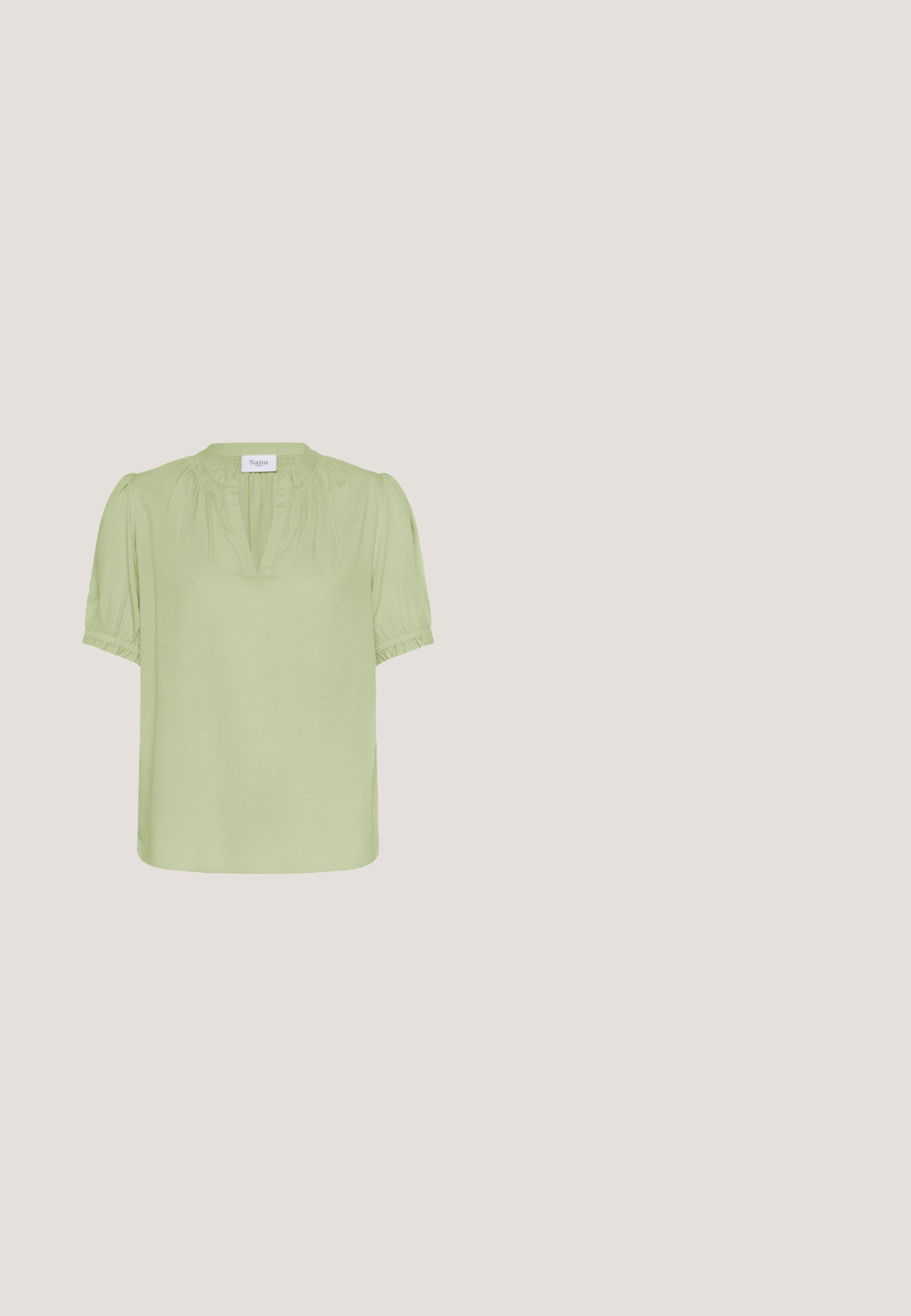 Lichtgroene blouse met korte mouwen, een geplooide halslijn en elastische manchetten. Gemaakt van textiel met structuur, met een relaxte pasvorm en rechte zoom.; Loszittende witte broek met pastelgele en roze bloemen en groene bladenprint, met een elastische tailleband met trekkoord.; Witte patenten leren slingback schoen met een spitse neus en een geometrische blokhak. Het interieur heeft een tan kleurige inlegzool en minimale zijsnedes.; Kattenoog zonnebril met een glanzend schildpadpatroon, verlopen bruine lenzen en gouden accentdetails op de slapen.; Off-white leren tote bag met gestikte bovenrand, voorzien van lange handvatten en een groen monstera bladvormig hangertje.; Gouden kettingarmband met witte parels, gouden en glanzende ster charms, en een sprankelende sterpendant met een karabijnsluiting en een verstelbare ketting.