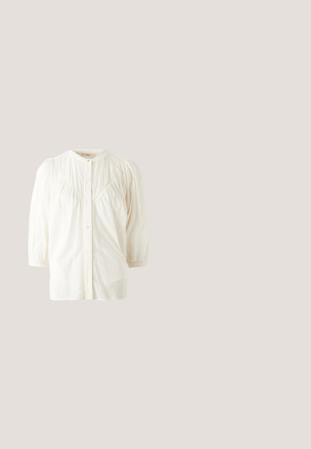 Blusa blanca de botones con cuello redondo, hombros plisados y mangas largas. Presenta sutiles rayas verticales y un corte relajado.; Vaqueros rectos de pierna azul oscuro con bolsillos delanteros, cierre de botón y costuras visibles en contraste sobre un fondo claro y liso.; Botín de cuero marrón con acabado mate, lados elásticos y un tacón grueso. Cuenta con una suela de goma texturizada y una pestaña de tirón.; Bolso tote de ante marrón con dos asas largas, con un bolsillo frontal, acompañado de una pequeña bolsa de cuero marrón con cremallera.; Collar tono oro con tres colgantes irregulares, lisos y con forma de guijarro, en una cadena delgada con cierre ajustable.; Cinturón de cuero marrón oscuro con una amplia hebilla cuadrada dorada, enrollado plano sobre una superficie blanca.