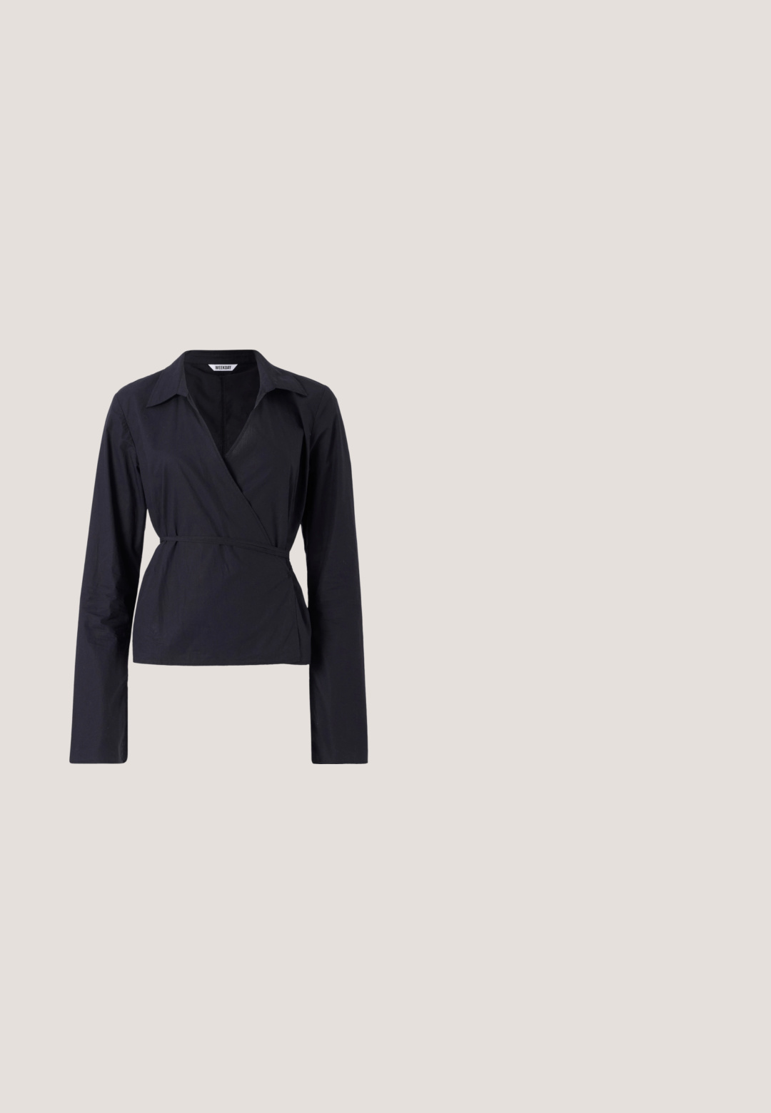Haut enveloppant noir en tissu léger. Dispose de manches longues, d'un col et d'une taille nouée pour une silhouette ajustée.; Pantalon beige taille haute, ajusté avec des plis, poches latérales, passants pour ceinture et fermeture éclair à l'avant.; Escarpin slingback noir à bout pointu avec deux brides à boucle dorée reposant sur une surface rembourrée argentée brillante.; Sac à main en cuir tissé noir au design décontracté, avec une sangle nouée et une petite clou doré décoratif en haut.; Boucles d'oreilles dorées avec une forme abstraite et organique, présentant une surface texturée et une fermeture à poussette.; Ceinture en cuir noir enroulée avec une boucle en métal doré brillant sur un fond clair.