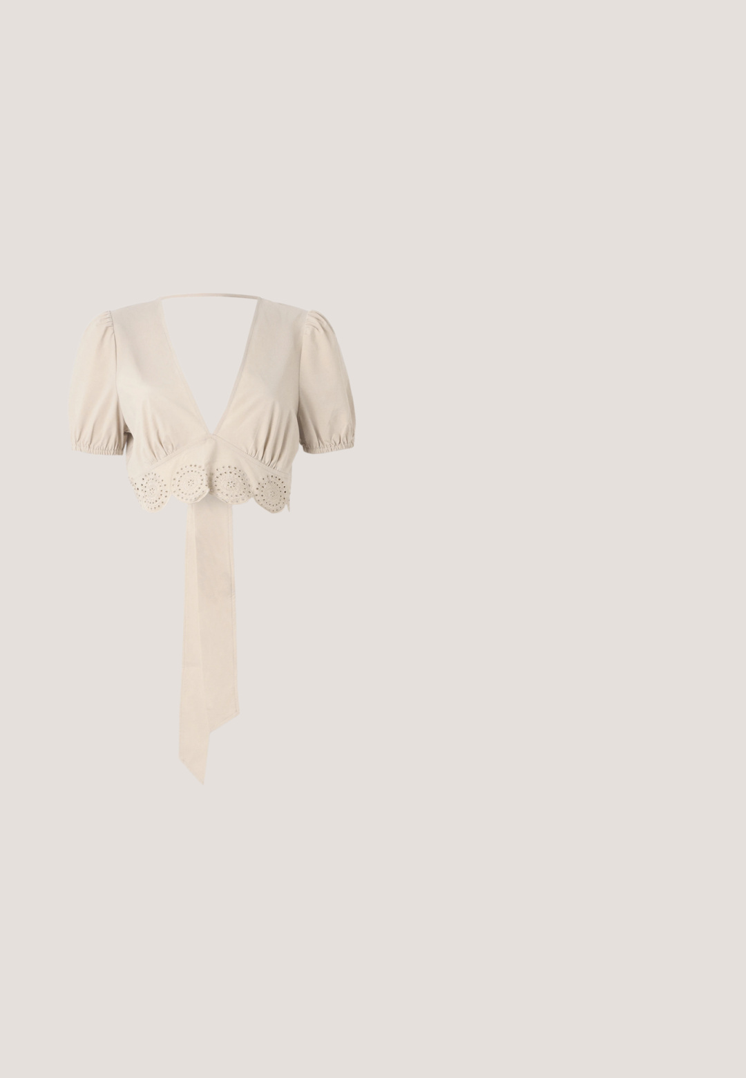 Beige cropped top met pofmouwen, diepe V-hals en decoratieve gaatjesrand aan de onderkant. Beschikt over een gebonden stoffen ceintuur. Vloeiende textuur.; Witte, losse broek gemaakt van een lichtgewicht, satijnachtige stof. Heeft een elastische tailleband met een geknoopt trekkoord en een subtiel patroon.; Witte hoge hak sandaal met een tule volant en parelaccenten; heeft een enkelbandje en een ronde neus ontwerp, glad oppervlak.; Zonnebril met grote, afgeronde vierkante verglazingen in een bruin verloop, omrand met goudkleurig metaal en dunne, gedetailleerde pootjes op een lichte achtergrond.; Crème kleurige clutch met geperst bloemmotief, gouden kettingriem en een klein metalen plaatje met de tekst "ANNA FIELD" op de voorklep.; Delicate dubbel gelaagde gouden ketting met gelijkmatig verdeelde kleine witte pareltjes op een eenvoudige lichte achtergrond.