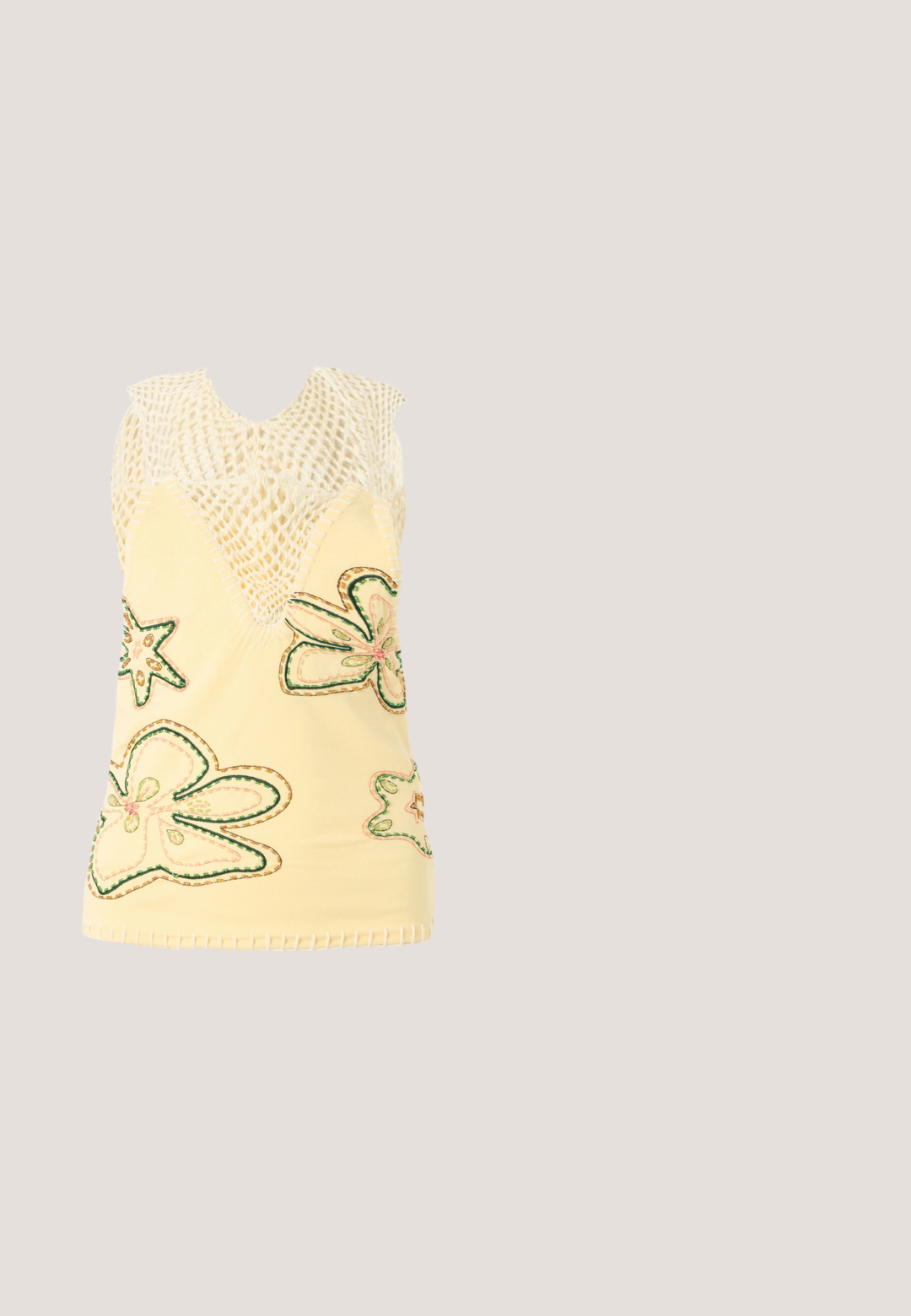 Haut sans manches jaune avec partie supérieure en maille crochetée et motifs brodés de papillons et d’étoiles multicolores sur la partie inférieure.; Jupe transparente vert clair avec une taille à cordon de serrage, texture lisse et design simple. La longueur tombe sous le genou.; Mule à talon haut à bout pointu jaune-vert avec trois fines lanières à boucles sur le devant et sur le côté sur fond blanc.; Lunettes de soleil ovales translucides vertes avec verres marron et marquage "QUAY" sur les branches, inclinées sur une surface blanche.; Petit sac à main rectangulaire vert clair avec deux poignées et une bandoulière amovible sur un fond uni.; Boucles d'oreilles en argent avec un design circulaire et une pierre précieuse verte au centre, présentant une texture lisse et une finition polie.