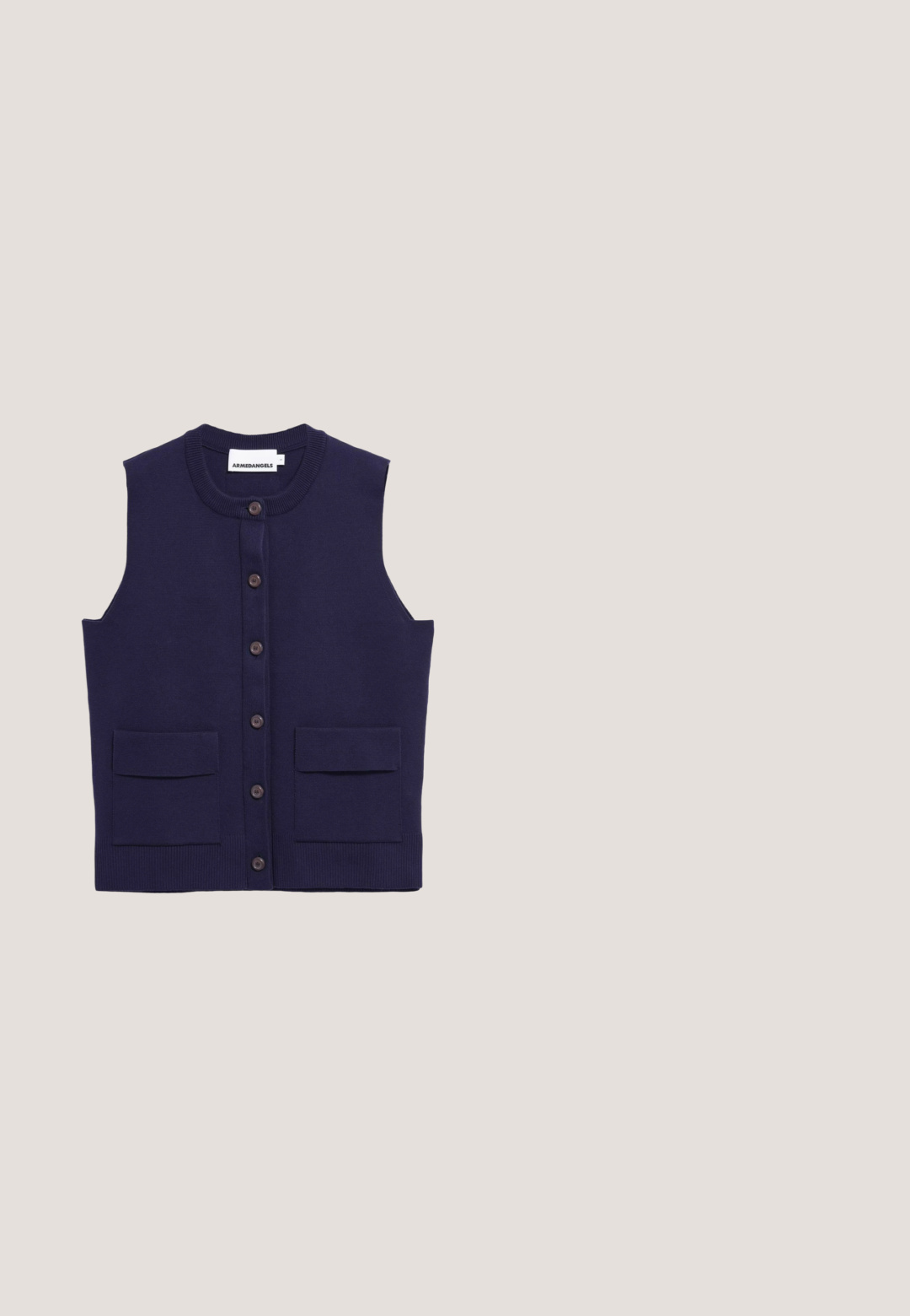 Marineblauw mouwloos gebreid vest met zes knopen in het midden en twee voorzakken met kleppen, gelabeld Armedangels.; Witte blouse met lange mouwen, knopen, kraag en klein blauw logo van een polospeler op de linkerborst.; Hoge taille, wijde pijpen crème kleurige broek met verticale gestikte strepen, voorzakken, riemlussen en een knoopsluiting in de taille.; Marineblauwe leren sneaker met gestructureerd oppervlak, ronde neus, crèmekleurige rubberen zool en gouden oogjes voor veters. Subtiele branding op de hiel.; Rechthoekige handtas in roomkleur met bovenhandvat, gouden beslag, sluiting met gegraveerd "TH"-logo en afneembare schouderriem.; Gouden ketting met een ontwerp van langwerpige rechthoekige schakel met een gladde afwerking. Beveiligd met een klassieke sluiting.