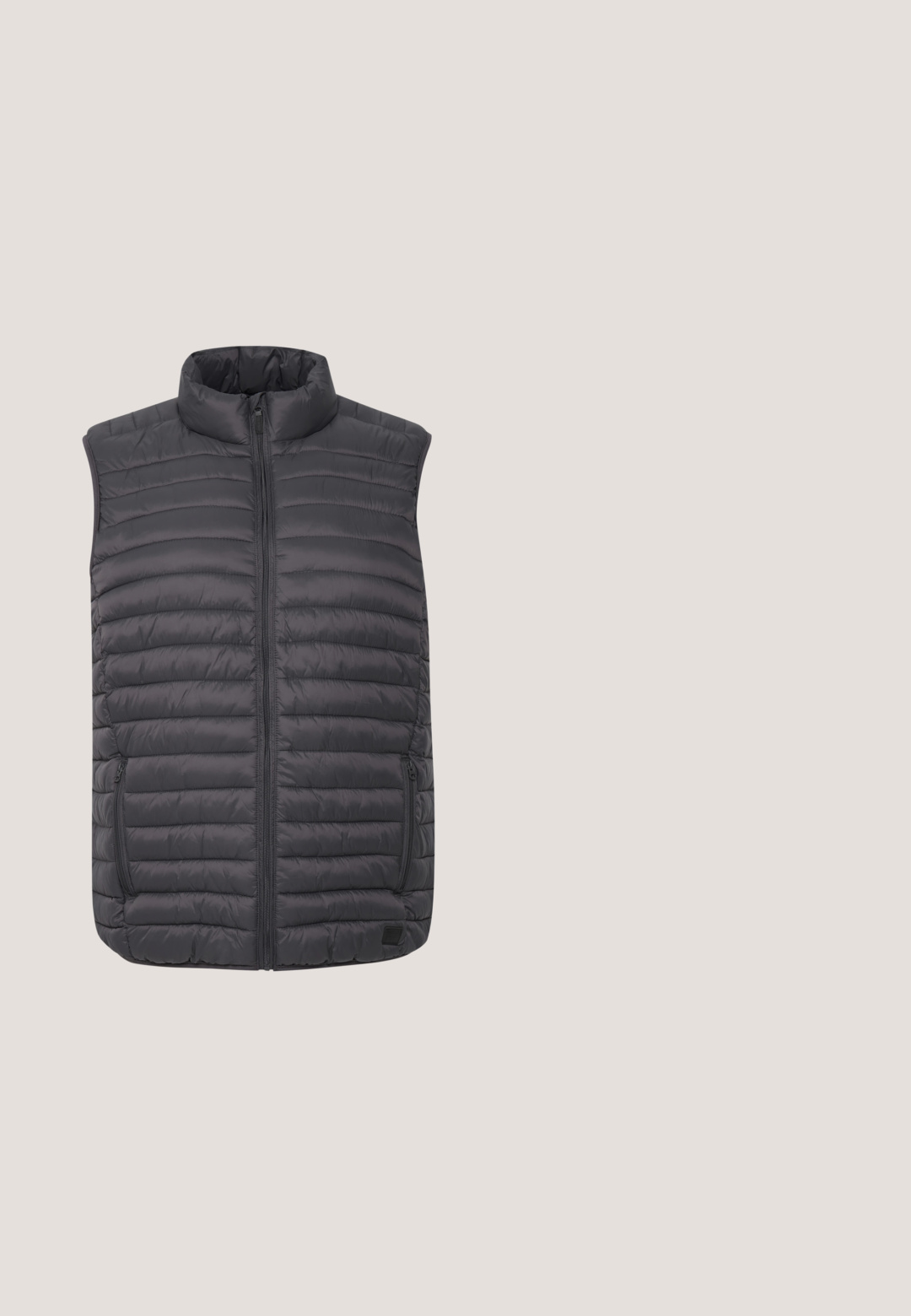 Grijze gewatteerde vest met een hoge kraag, volledige rits aan de voorkant en twee ritszakken aan de zijkant. Horizontaal gestikt ontwerp met een gladde textuur.; Lichtgrijze crew-neck sweatshirt van zachte katoen. Heeft lange mouwen, ribgebreide manchetten en boorden, en een eenvoudig, naadloos ontwerp.; Lange mouwen overhemd met knopen in lichtbeige katoen. Heeft een klassieke kraag, volledige knoopsluiting aan de voorkant en manchetten met knopen. Glad van textuur.; Zwarte jeans van katoen, met een klassieke snit, vijf zakken en een metalen knoopsluiting. Glad textuur met rechte pijpen.; Zwartbruine lage sneaker met witte zool en veters, zwevend boven een beige tapijt in een ruimte met neutrale tinten.; Zwarte schoudertas gemaakt van gestructureerde stof, met een ritssluiting, verstelbare schouderriem en een reliëflogo op het voorpaneel.