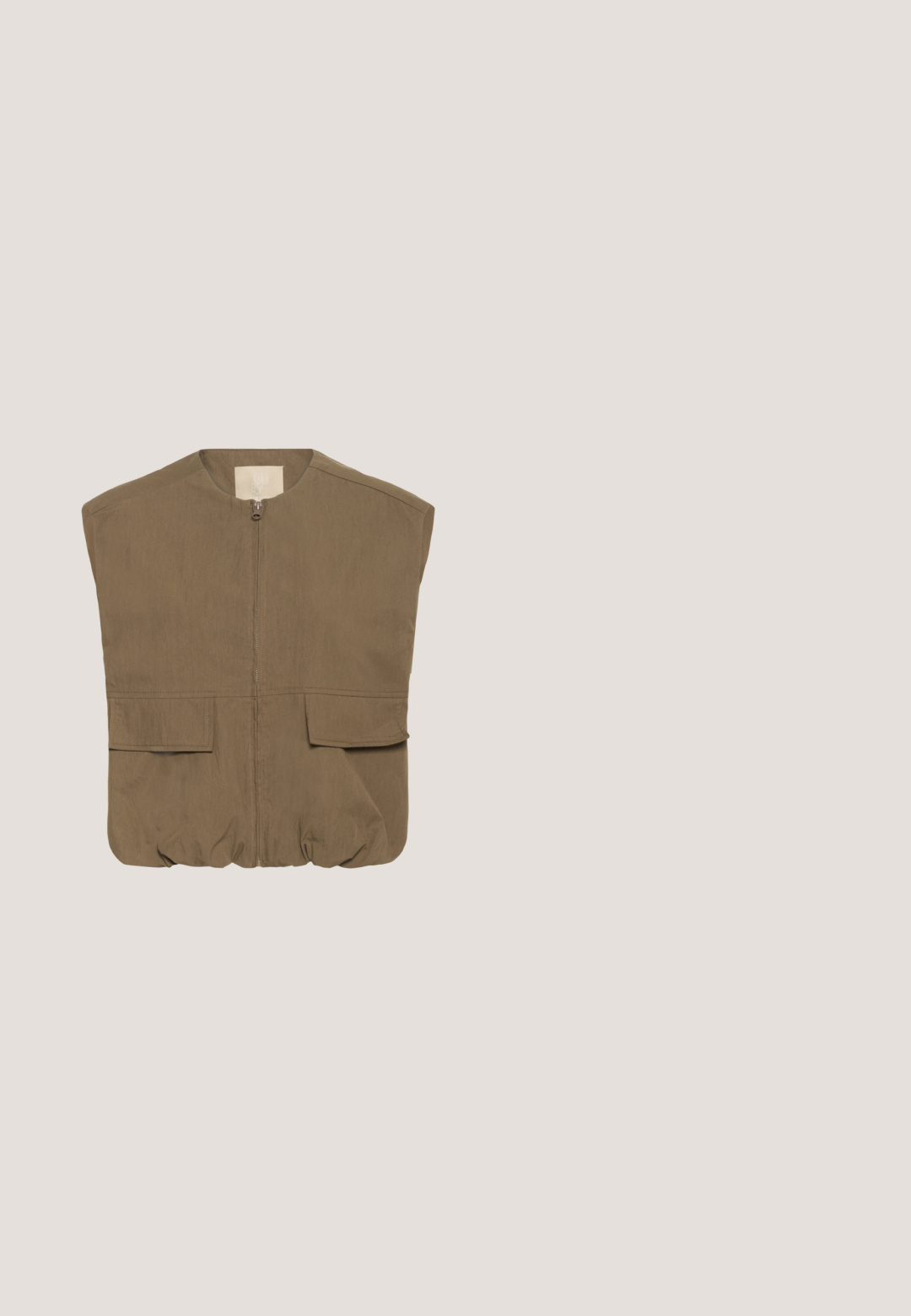 Chaleco sin mangas color caqui con cuello alto, cremallera frontal, dos grandes bolsillos parche y dobladillo elástico. Fabricado en una tela ligera y texturada.; Camiseta blanca de manga corta hecha de algodón suave. Presenta un cuello redondo y un diseño simple y sin costuras, sin adornos ni patrones.; Pantalones de pierna ancha de color verde claro, hechos de un material suave, con una cintura elástica y cordón ajustable, y dos bolsillos delanteros.; Zapatilla deportiva de malla beige con suela blanca gruesa, cordones delanteros, tiradores en la lengüeta y el talón, y detalles sutiles con la marca en el talón.; Bolso acolchado beige con una correa de hombro removible, dos asas cortas y una forma rectangular. Cuenta con un parche de logo en la parte frontal.; Anillo de plata con un acabado suave y pulido, que presenta un diseño abierto y único que se curva e intrecha en una forma elegante.