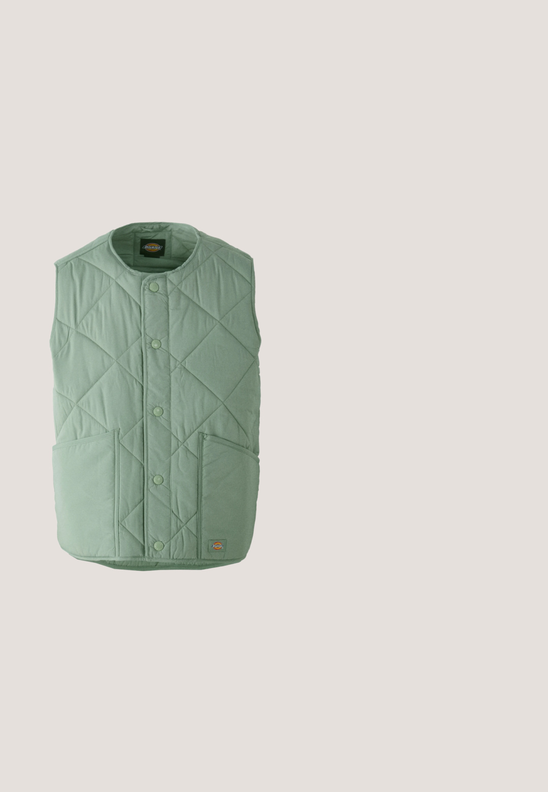 Gilet matelassé vert clair avec un col rond, des boutons-pression, deux poches avant et une étiquette de marque en bas à droite.; Pull en maille blanc à manches longues avec col ras du cou et petit logo noir Dickies sur le haut à gauche de la poitrine.; T-shirt à manches longues blanc en coton. Présente un petit logo doré sur la poitrine et un col rond. Design simple et coupe standard.; Pantalons larges noirs en tissu durable. Fermeture à bouton et poches latérales. Texture lisse avec un design épuré.; Baskets crème et bleu marine avec semelle marron, lacets blancs et logo "Globe", flottant au-dessus de marches en béton texturé dans un environnement ombragé en plein air.; Sac bandoulière compact vert olive avec sangle noire, poche zippée à l'avant avec tirettes rouges, et patch "montagne" avec des rayures de coucher de soleil.
