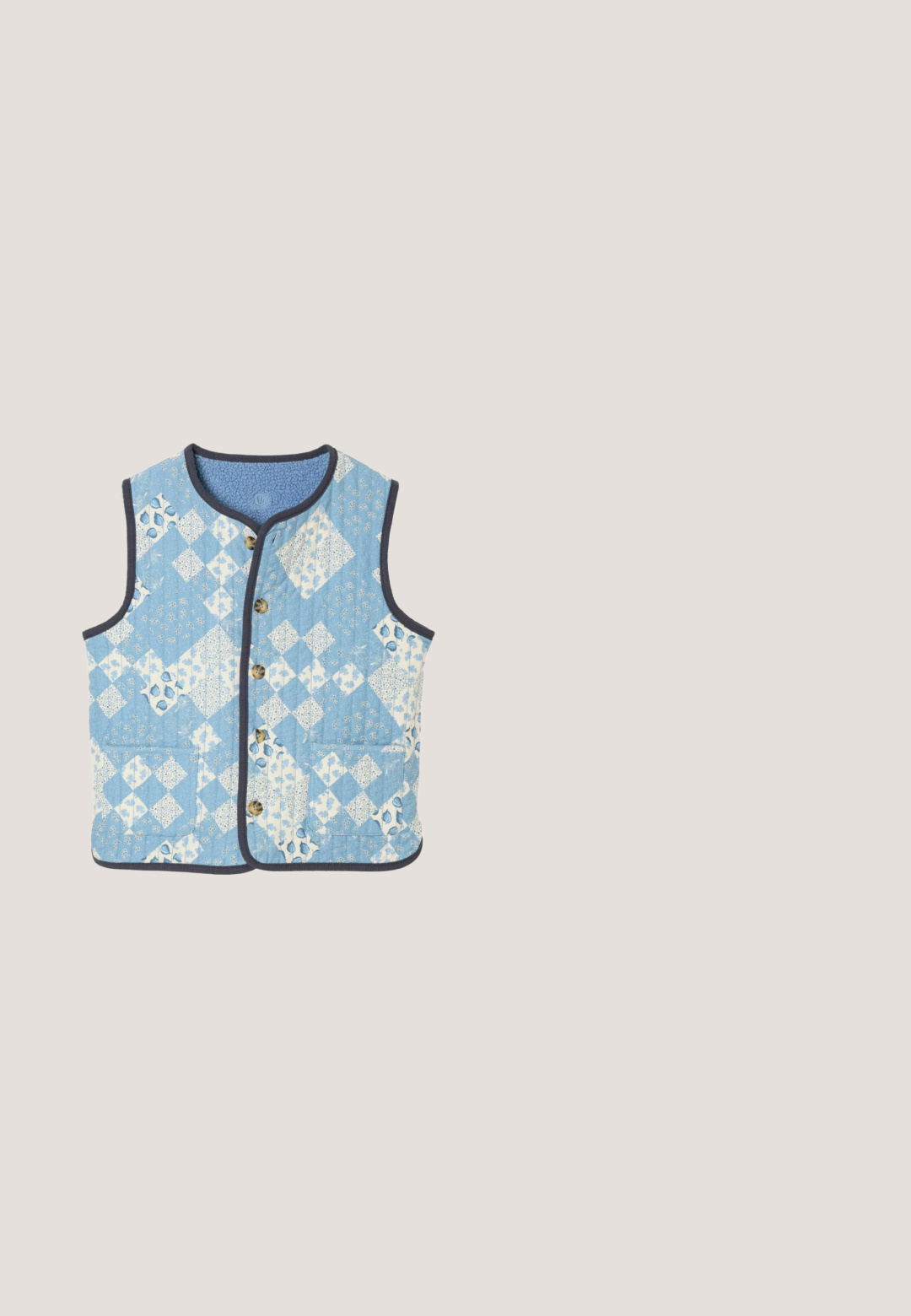 Ærmeløs quiltet vest med blåt og hvidt blomsterpatchworkmønster, rund halsudskæring, knapper foran, to forlommer og mørk kant.; Lyseblå sweater med rund halsudskæring, ribbede manchetter og nederkant, har en tekstureret bjørn emblemet og logo i subtil relief. Blødt strikket material.; Lys blå langærmet skjorte med knapper, hvide lodrette striber, kravedesign, en lomme på venstre bryst og sammenfaldne ærmer ved manchetterne.; Lyseblå bukser med vide ben, hvide lodrette striber, hvide broderede blomsterpatroner, elastisk talje og bølget kant.; Lyseblå ruskind moccasin loafer med lav brun sål, rundet tå og syninger som detaljer på oversiden.; Blomsterpræget skuldertaske i lyseblå og hvid. Fremstillet af slidstærkt stof med to håndtag og en struktureret rektangulær form.