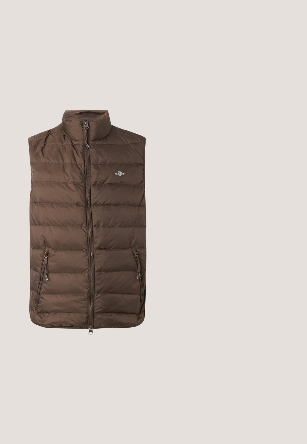 Hnedá prešívaná vesta bez rukávov s predným zipsom, dvoma bočnými vreckami na zips a malým vyšívaným logom na hrudi.; Olivovo zelená mikina s kapucňou z bavlny, so skladacou kapsou na prednej strane a námornícky vyšívaným logom s krídlami. Rebrované manžety a lem.; Tmavomodré tričko s krátkym rukávom a okrúhlym výstrihom s malou obdĺžnikovou nášivkou loga na ľavej strane hrudníka.; Modré džínsy z denimovej látky s vyblednutým umývaním, ktoré majú päť vreciek, zips na uzatvorenie a priame nohavice. Švy sú prešité kontrastnou niťou.; Športová teniska s čiernym koženým zvrškom, béžovými a hnedými semišovými akcentmi a mentolovo zeleným opätkom. Má textúrovanú gumovú podrážku a viazací dizajn.; Olivovo zelená bedrová taška s čiernym zipsom a červeným ťahákom, nastaviteľným čiernym popruhom a farebnou nášivkou s logom Montagne uprostred na prednej strane.