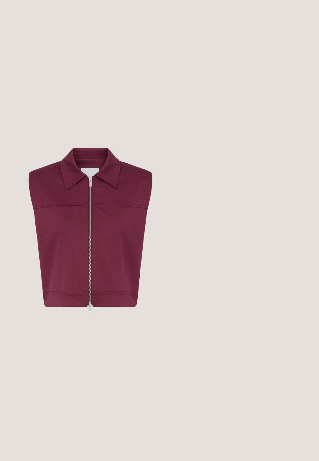 Veste sans manches bordeaux avec un large col et une fermeture éclair argentée sur toute la longueur à l'avant, présentée sur fond blanc.; Top femme à manches courtes de couleur violet foncé avec encolure bateau et détail bouton à l'épaule, étiquette indiquant "CECIL" à l'intérieur du col.; Pantalon bordeaux en tissu doux et extensible, avec une taille élastique à cordon de serrage, des plis à l'avant et des jambes fuselées. Texture lisse sur l'ensemble.; Baskets basses en suède violet foncé avec talon blanc, bandes latérales blanches et semelle épaisse texturée beige, vue de côté.; Lunettes de soleil cat-eye violettes avec verres dégradés, monture épaisse en plastique et détails dorés sur les branches. Texture lisse et brillante.; Sac cabas en daim bordeaux foncé avec poignées arrondies et logo "nat & nin" discret au centre devant.