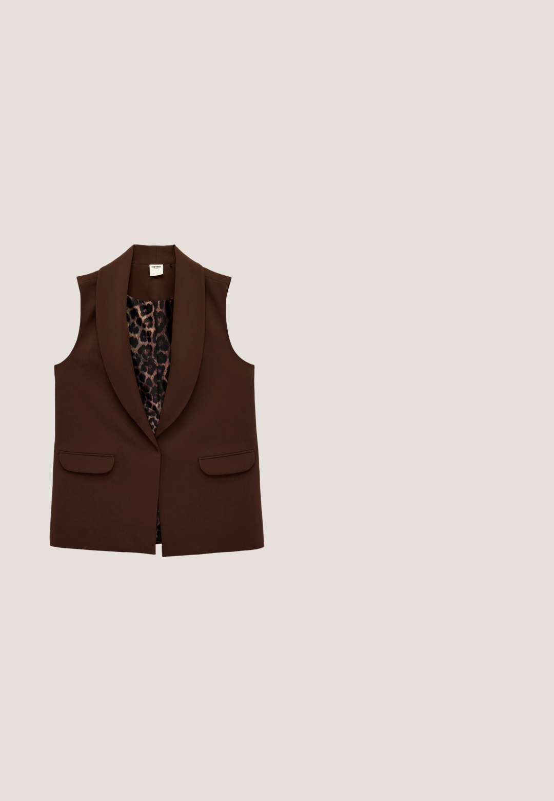 Blazer sin mangas de color marrón oscuro con solapas anchas y forro interior de estampado de leopardo, con dos bolsillos delanteros con solapa.; Camisa corta de botón marrón con cuello, mangas largas y botones en contraste. Tejido suave con detalles de costura sutiles.; Pantalones marrones de pierna ancha con una cinturilla alta, confeccionados en tela suave y con pliegues frontales, que ofrecen un ajuste holgado y una caída fluida.; Zapatos de plataforma de ante marrón con punta redonda, detalles recortados y una suela resistente, acompañados de una falda de mezclilla en un entorno de suelo de madera.; Gafas de sol marrón carey con lentes ovalados, que presentan un marco delgado y un pequeño acento metálico en el lateral. Acabado texturizado y pulido.; Bolso de mano de patchwork con texturas de cebra, marrón y estampado animal. Los materiales incluyen ante y cuero, con una correa desmontable y cierre de cremallera.