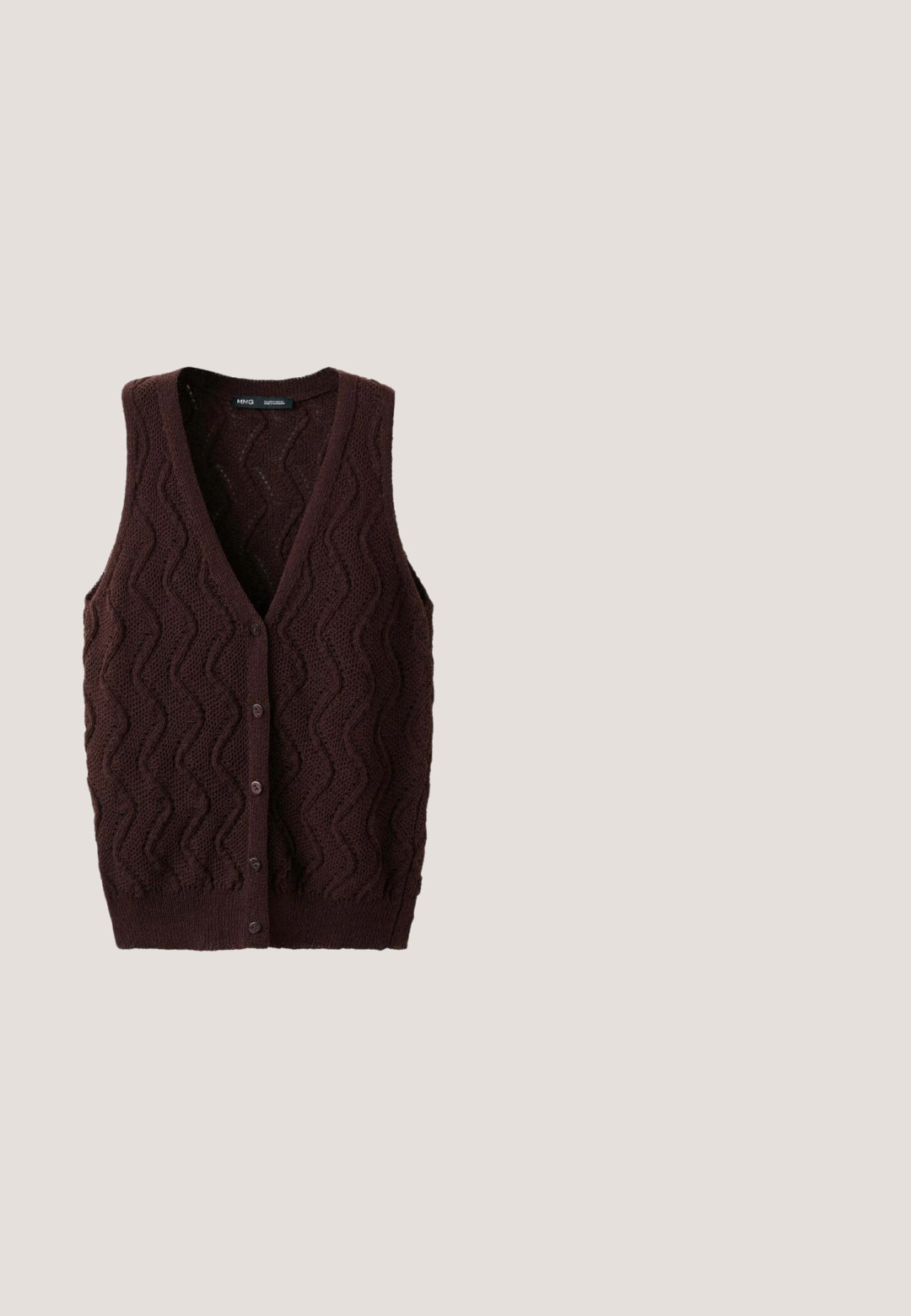 Gilet sans manches en maille marron foncé avec motif en vagues et boutons devant, col en V et ourlet côtelé.; Chemise marron à manches longues et col roulé, en tissu doux, présentée sur un fond blanc.; Pantalons larges marron avec une texture lisse, dotés de plis avant, d'une fermeture à bouton et d'un design ajusté.; Bottine Chelsea en daim marron foncé avec panneau latéral élastique noir, languette arrière et semelle basse en caoutchouc noir.; Lunettes de soleil rectangulaires marron avec une finition brillante, dotées d'une monture plus épaisse et de verres dégradés subtils. Accentuée par un logo 'vogue' en argent.; Trousse de toilette rectangulaire marron foncé avec fermeture éclair et petite étiquette de marque argentée à l'avant sur fond blanc.