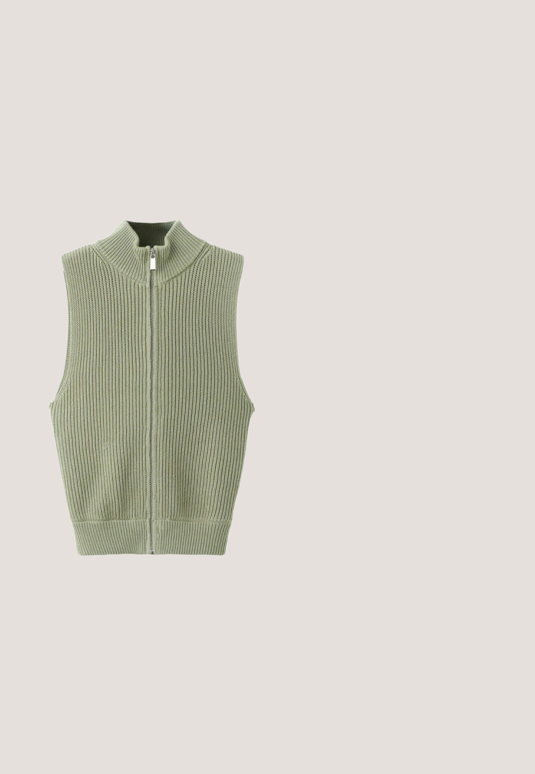 Saliegroene geribbelde gebreide mouwloze vest met hoge kraag en ritssluiting aan de voorkant, plat uitgestald op een witte achtergrond.; Lichtbeige korte mouwen gebreid top met een bevestigde sjaaldetail die rond de halslijn hangt.; Olijfgroene, brede pijpen broek gemaakt van zachte, rekbare stof met een elastische tailleband en verstelbare trekkoord. Zonder patronen of versieringen.; Bruine suède instappers met een afgeronde neus, een gladde textuur en zilverkleurige ronde accenten langs de zijkant. Zwarte zool contrasteert met het bovenwerk.; Rechthoekige schildpadzonnebril met bruin getinte glazen en een dik montuur.; Bruine suède schoudertas met een enkele band, zachte, slordige vorm, zonder zichtbare sluitingen of versieringen.