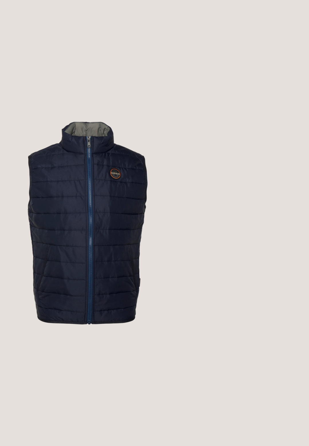 Chaleco acolchado azul marino con cuello alto, cierre frontal de cremallera y patrón de acolchado horizontal. Cuenta con bolsillos laterales y un detalle de logo en el pecho.; Camiseta azul marino de manga corta con cuello redondo y bolsillo en el pecho que muestra un pequeño logo sobre un fondo liso.; Vaqueros de mezclilla azul con un acabado desgastado, diseño de pierna recta, estilo de cinco bolsillos y acentos de hardware metálico en tono cobre.; Zapatilla deportiva azul marino y gris con materiales mixtos, presenta una parte superior texturizada, detalles naranjas, una suela resistente y un talón blanco en contraste.; Gafas de sol con lentes grises y un marco metálico. Presentan una forma angular y varillas delgadas con detalles sutiles. Sin adornos prominentes.; Bolso bandolera compacto de color gris oscuro con bolsillo delantero con cremallera y emblema de logo negro, correa de hombro ajustable con nombre de marca visible.