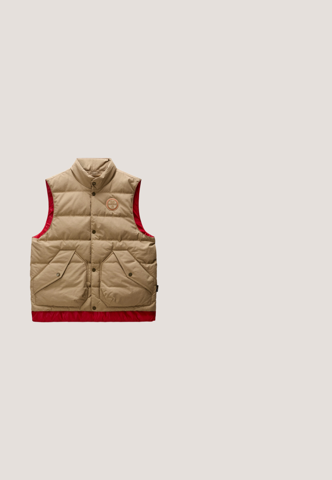 Beige en rode puffer-vest met hoge kraag, drukknoopsluiting, twee voorzakken met klep en een rond logo op de borst.; Bruine trui met kwart rits en donkerbruine outdoor-thema graphics, waaronder bloemen, dieren, bomen en de merknaam Napapijri.; Witte katoenen T-shirt met korte mouwen, ronde hals en een klein bedrukt logo op de linkerborst. Heeft een ontspannen, rechte pasvorm.; Donkerblauwe denim jeans met een rechte pijp, voorzien van oranje stiksels, een ritssluiting en voorzakken. Glad oppervlak en een standaard tailleband.; Donkerbruine suède sneaker met vetersluiting, bruine leren zijkantdetail, zwarte zool met zigzagpatroon en witte hielaccent.; Bruine leren reistas met twee handvatten, een voorvak met ritssluiting en een verstelbare schouderriem op een witte achtergrond.