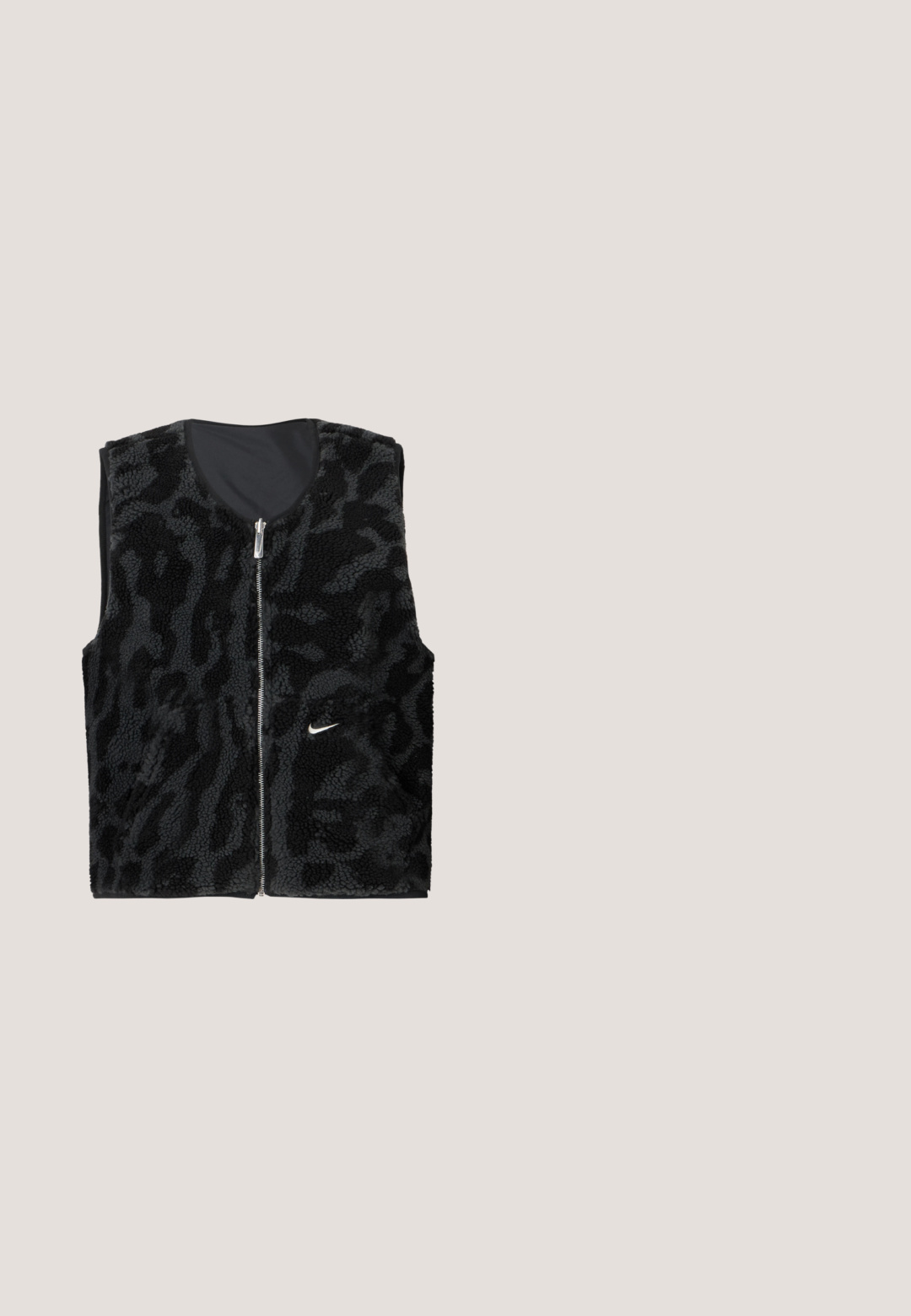 Sort fleece vest med lynlås foran, der har et tekstureret dyreprintdesign og et lille hvidt Nike-logo på venstre side.; Lilla cropped top med et struktureret stof, firkantet halsudskæring, korte ærmer og ribbet kant, med subtile mørke mønstre gennemgående.; Vinrøde sweatpants med vide ben og snøre i taljen, med lille hvid og gul Nike-logo samt teksten "Athletic Club" på højre lår.; Rød syntetisk sportssko med quiltet design, sorte accenter og hvid sål. Har snørebånd og en polstret krave for komfort.; Sort denim skuldertaske med dobbelte rebstropper og knuder i enderne på hver side, sat mod en ensartet hvid baggrund.; Et par polerede sølv halvmåneformede hoop øreringe med klare plastikbagsider på en hvid overflade.