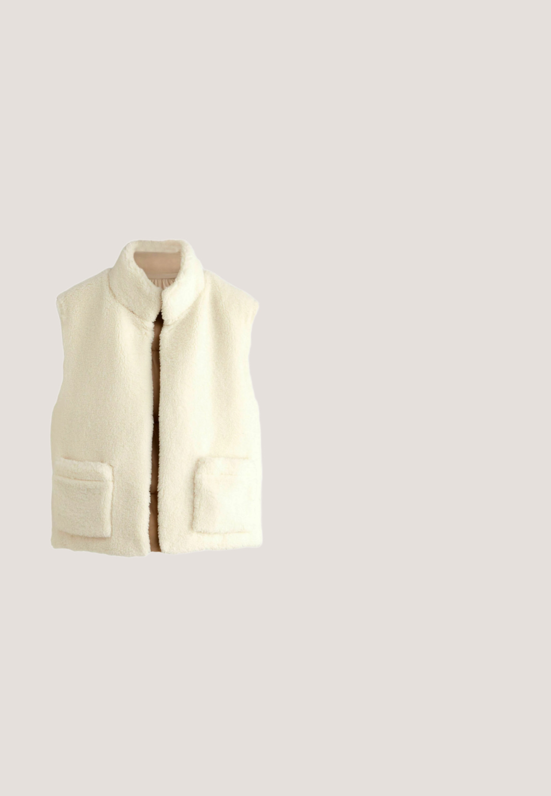 Beige, ärmellose, isolierte Weste mit hohem Kragen, weicher cremefarbener Innenauskleidung und gestepptem Textur. Zentrale Vorderseite mit Verschluss ohne sichtbare Beschläge.; Cremefarbener Langarm-Pullover mit halbem Reißverschluss, hohem Kragen, Seitentaschen und verstellbaren Kordeln am Saum.; Langärmliges, eng anliegendes Oberteil aus cremig-weißem geripptem Material. Verfügt über einen hohen Halsausschnitt und fransige Saumdetails für ein strukturiertes Aussehen.; Beige Leggings mit hohem, breitem Bund, gefertigt aus einem weichen, elastischen Stoff. Gerade Beinform ohne sichtbare Nähte oder Muster.; Braune Wildleder-Sneaker mit dicker beiger Sohle, weißen, flauschigen Schnürsenkeln, die oben aufgerollt sind, und kuscheligem Futter am Kragen.; Beige rechteckige pelzige Handtasche mit braunen Griffen und dem auf der Vorderseite eingeprägten Markennamen "LIU JO".