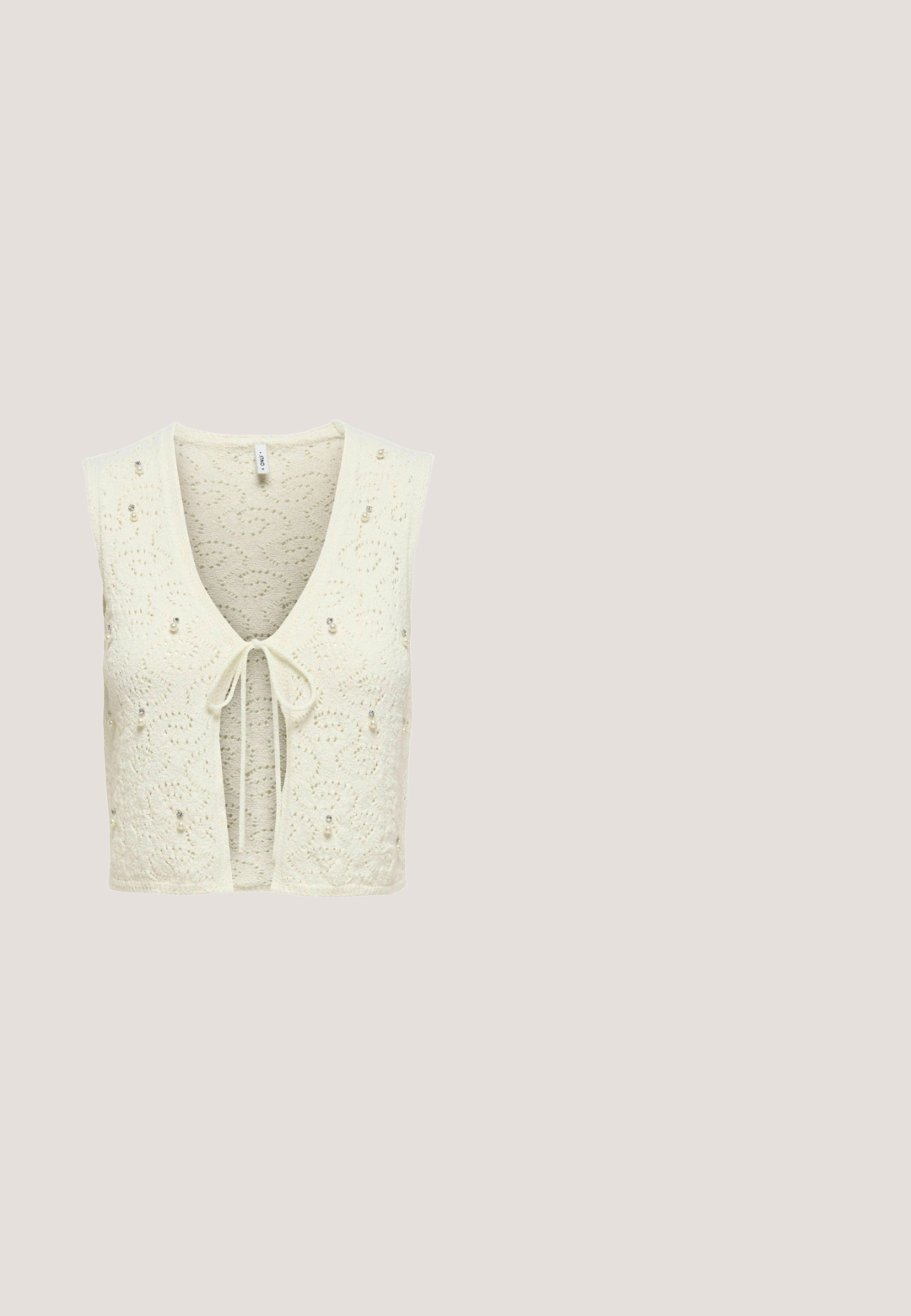 Chaleco de punto recortado en crema con un escote profundo en V, cierre con lazo y detalles decorativos de cuentas. Presenta un patrón floral texturizado en toda su superficie.; Top blanco de algodón con detalle de smocking, encaje en el dobladillo y tirantes ajustables con volantes. Tejido ligero, corte relajado.; Pantalones cortos de mujer de talle alto color crema con bordado floral de ojales y detalles de bajo festoneado.; Sandalia plana marrón con tira de flecos, decorada con una fila de cuentas blancas y colgantes dorados con temática marina, incluyendo una estrella de mar y una concha.; Gafas de sol estilo ojo de gato con patrón carey y lentes marrones degradados, colocadas sobre una superficie blanca.; Bolso redondo beige de crochet con un patrón circular y un asa trenzada unida por cierres metálicos dorados.