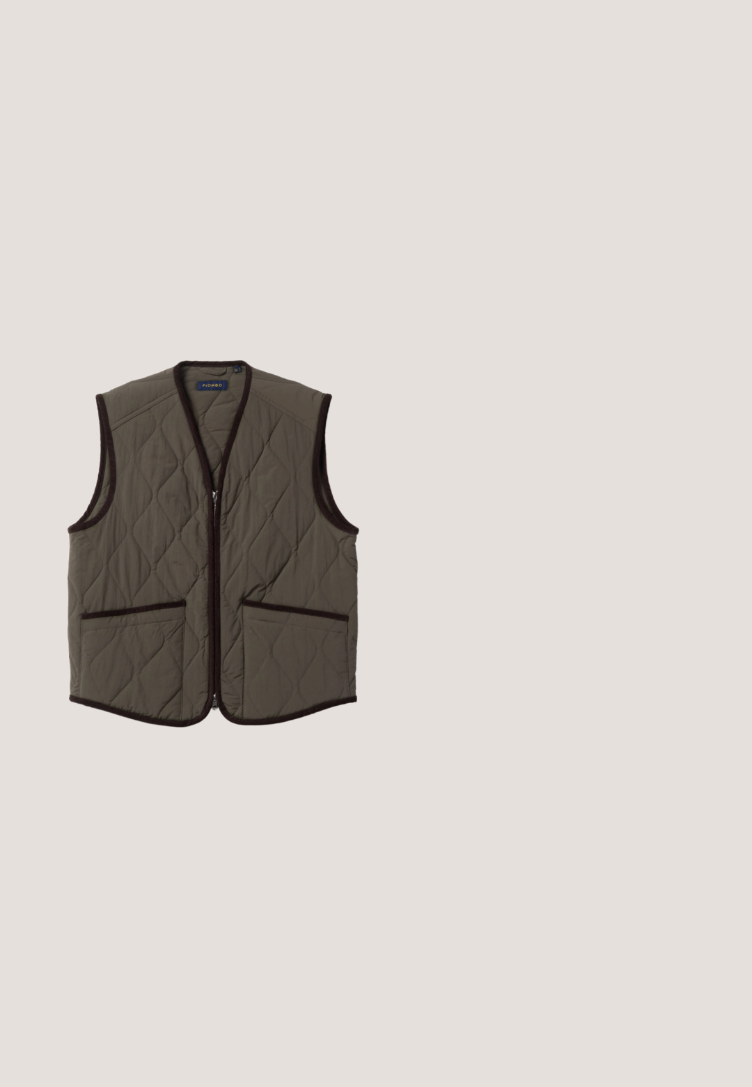 Chaleco acolchado sin mangas en verde oliva con ribete marrón oscuro, cremallera frontal y dos bolsillos delanteros.; Suéter de punto verde oscuro con mangas largas y cuello alto con media cremallera, colocado sobre un fondo blanco.; Camiseta gris claro de manga larga con cuello redondo y costuras raglán, colocada plana sobre fondo blanco.; Pantalones de pana color verde oliva con cintura elástica, dos bolsillos laterales y un diseño de pierna recta con sutiles estrías verticales.; Botines de ante marrón con punta redondeada, costuras mínimas y suela de goma gruesa y texturizada. Presenta un diseño de cordones y una pestaña en el talón.; Bolsa de deporte cilíndrica verde aceituna con doble asa, correas ajustables y bolsillo frontal sobre fondo blanco.