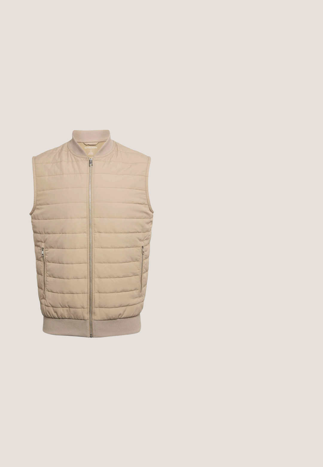 Beige quiltet ærmeløs vest med lynlås foran, sidelommer og ribstrikket krave og kant. Glat stoftekstur.; Kortærmet skjorte med krave i lys beige stof, der har en lomme foran og en knaplukning med fem knapper.; Beige bukser med snøre i taljen, elastisk linning, for-rynker og lige ben.; Beige Birkenstock klip lavet af ruskind med en korksål, der har en frontrem og en struktureret gummisål.; Gennemsigtige beige rektangulære solbriller med gradient brune linser, vinklet visning der viser stellet og stængerne.; Lysebrun rektangulær toilettaske med brun læderkant, sidehåndtag og frontmærke i læder prentet med "Howard London."