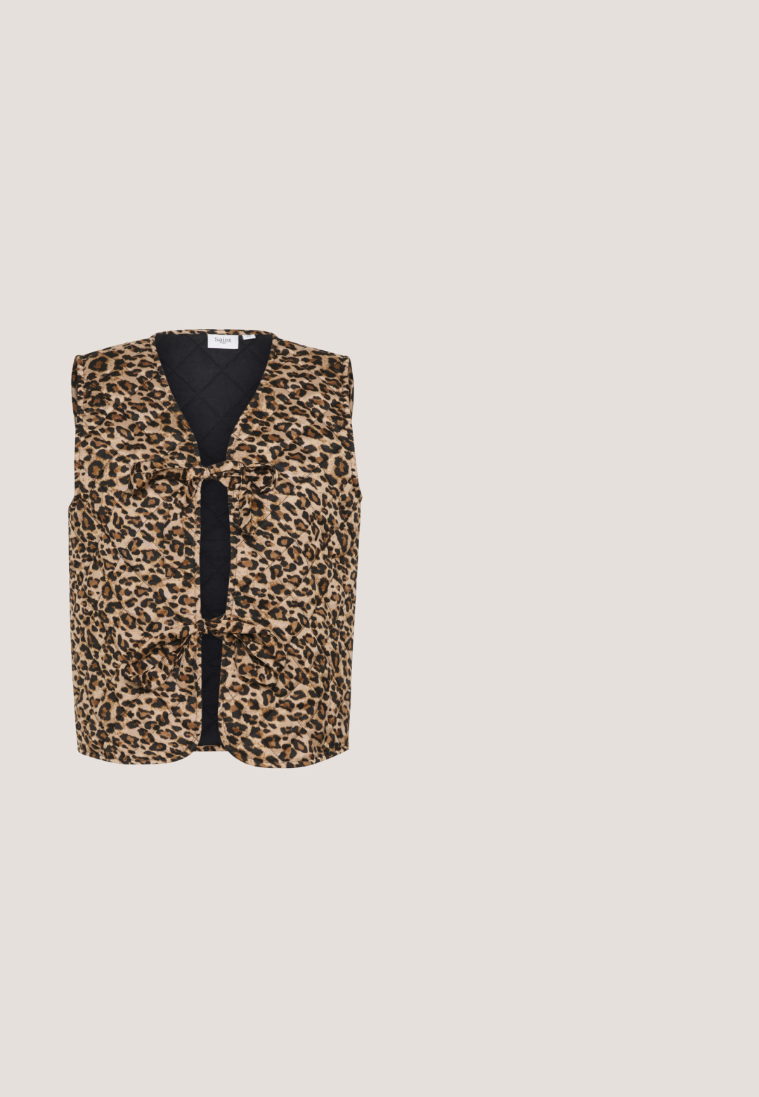 Chaleco de estampado de leopardo con textura acolchada, escote en V profundo y lazos en el frente, con un panel trasero negro sólido. Tela ligera.; Top de manga larga con cuello alto, estampado de leopardo en tonos marrón y beige, con detalles de fruncido en la parte frontal para dar forma.; Pantalones de estampado de leopardo hechos de tela ligera, con un diseño de pierna ancha, cintura elástica y un fondo beige con manchas marrones oscuras.; Zapatilla gruesa de plataforma negra y marrón con paneles de estampado de leopardo, suela gruesa y acanalada y cierre de cordones.; Pequeño bolso bandolera rectangular con estampado de leopardo en marrón y negro, correa de cuero negra y cierre de cremallera.; Aro de oro con un colgante en forma de corazón translúcido de ámbar oscuro pulido, suspendido en el centro.