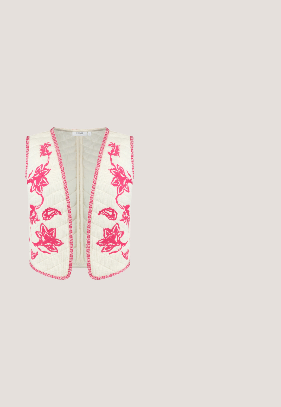 Gequilte crèmekleurige vest met roze bloemenborduursel en bijpassende bies, met een open voorkant en zonder mouwen, ontworpen om te lagen.; Felroze cropped tanktop met dunne dubbele schouderbandjes en mesh inzetten aan de zijkanten.; Felroze broek met wijde pijpen, verticale strepen en zijstrikjes, met een elastische tailleband voor een comfortabele pasvorm.; Roze lakleren sandalen met hakken, een vierkante punt, smalle banden en een geometrische blokhak. Met een gespdetail op de band.; Felroze geweven handtas met twee voorvakken, grote ronde knopen en één afgeronde handgreep tegen een egale lichte achtergrond.; Verstelbare roze gevlochten armband met een gouden vlindertashanger, versierd met kleine witte kristallen en een centraal pareldetail.