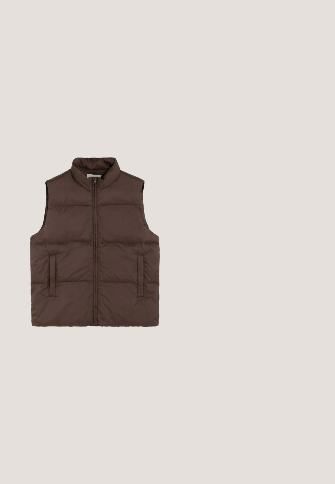 Chaleco marrón sin mangas acolchado con cremallera frontal y dos bolsillos laterales, diseñado para mantener el calor y para uso casual.; Suéter marrón de punto acanalado con cuello redondo y mangas largas. Presenta un dobladillo y puños ajustados. La etiqueta muestra el nombre de la marca NN07.; Camiseta marrón de manga corta con cuello redondo y tejido sutilmente texturizado, extendida sobre un fondo blanco.; Pantalones de pierna ancha en color gris, confeccionados en una tela suave, con cierre de botón y dos bolsillos laterales. Diseño simple y limpio sin patrones visibles.; Zapatilla baja de ante gris con suela de goma marrón, cordones y lengüeta en el talón, vista lateral sobre fondo blanco.; Bolso de viaje de cuero marrón con asas redondeadas, correa de hombro ajustable, diseño minimalista, textura lisa y detalles de costura visibles.