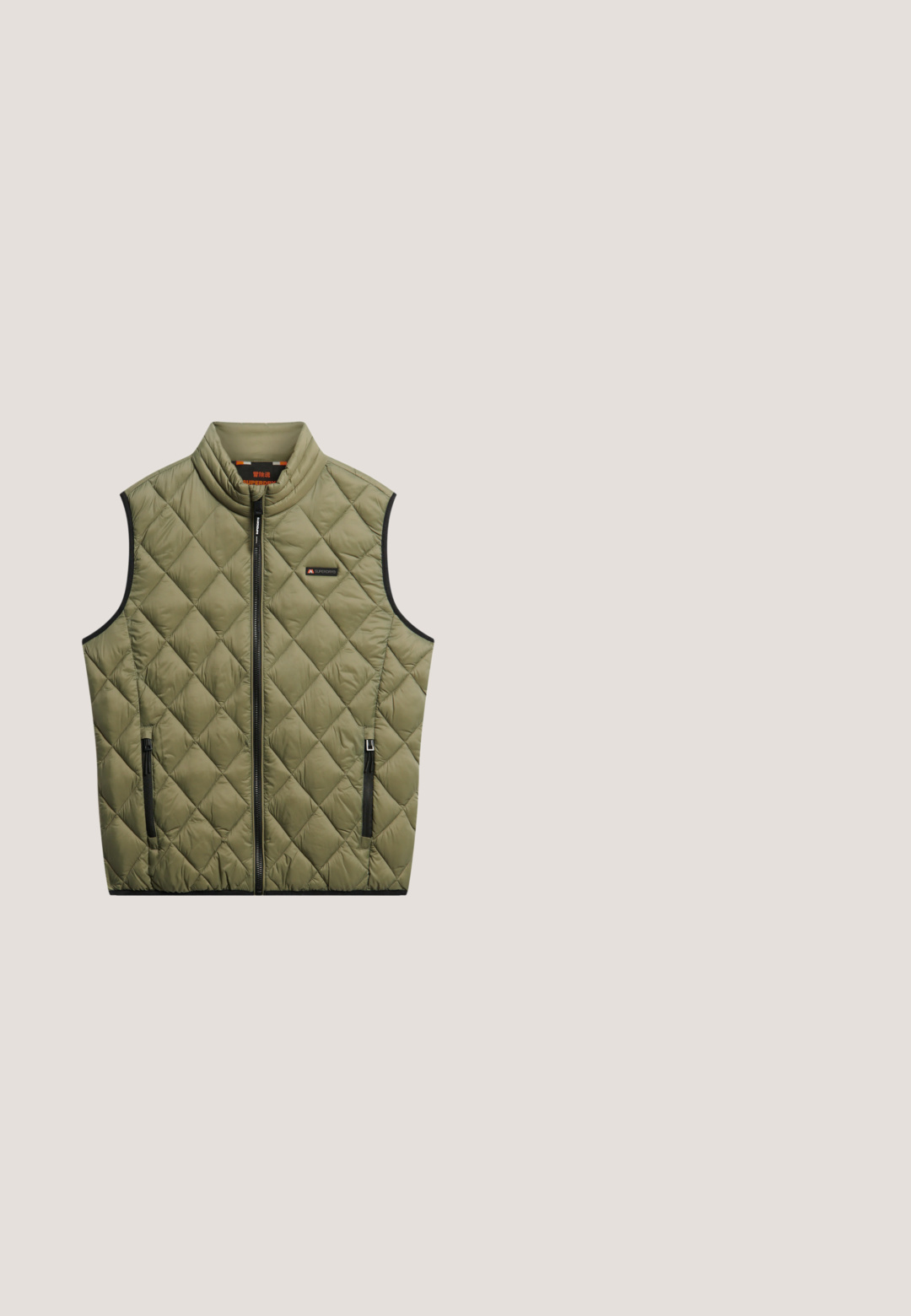Gequilted olijfgroen vest met hoge kraag, zwarte rits en zijvakken. Heeft een subtiele merklogo op de borst en een gladde textuur.; Grijze, gestructureerde pullover met een kwart ritssluiting en een kenguruzak. Heeft een subtiel ruitpatroon en een klein geel logo op de borst.; Bruine canvasjas met een kraag, knopen aan de voorkant, twee opgestikte zakken aan de voorkant en een klein logo op de onderste zak.; Donkerblauwe denim jeans met een recht model, vijf zakken en contrasterende stiksels op de naden. Gladde stofstructuur.; Bruine en grijze suède sneaker met tan strepen, vetersluiting, beige tussenzool en geribbeld bruine buitenzool, zijaanzicht.; Zwarte rechthoekige tas van gladde stof, met een ritsluiting, een zijhandvat en een klein logopatch aan de voorkant.