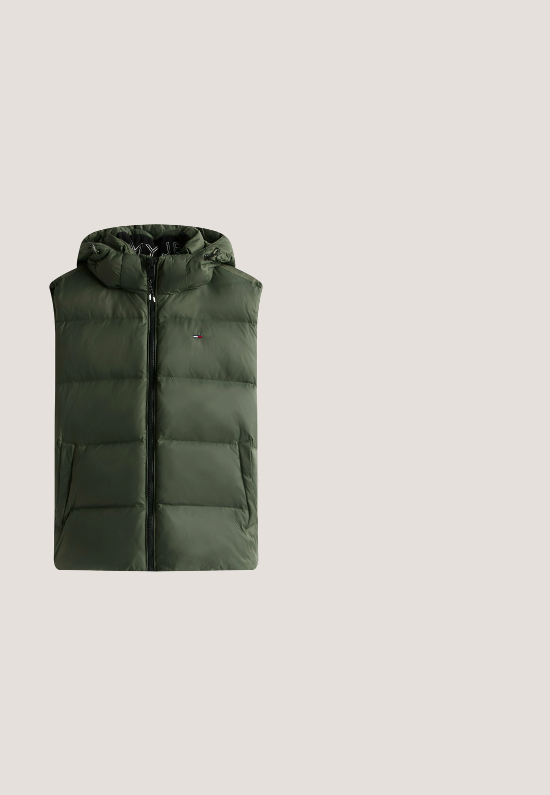 Grøn polstret vest med lynlås foran, justerbar hætte og logoakcent. Har quiltet tekstur og sidelommer til opbevaring.; Mørkegrøn hættetrøje med frontlomme og snoretræk, med teksten "Tommy Hilfiger American Classics Est. 1985" og logo i hvidt på brystet.; Kortærmet, rund hals T-shirt i blågrøn farve med lille "Tommy" skrift og bynavne trykt på venstre bryst samt et lille flag på venstre ærme.; Lysegrønne joggers med elastisk talje og snor, der har to sidelommer og tapered manchetter ved anklen.; Hvide lædersneakers med grønne og beige accenter, der har en tekstureret sål, rund tå og traditionelt snørrebåndsdesign.; Lille firkantet mørkegrøn crossbody-taske med frontlomme med lynlås og Tommy Jeans logo-patch i nederste højre hjørne.