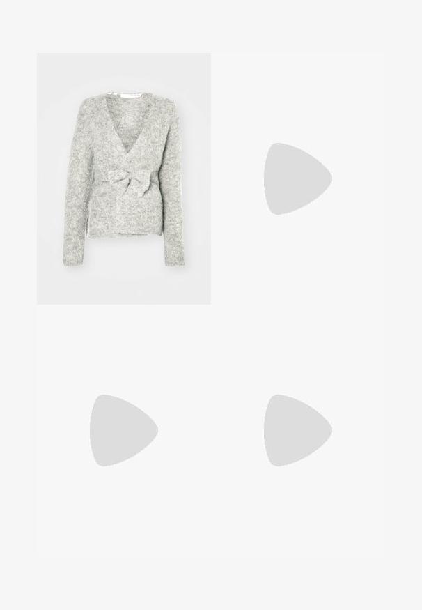 Gilet tricoté gris avec un col en V, des manches longues et un détail de nœud à l'avant. Texture douce avec une coupe ample et un motif chiné subtil.; Chemise blanche à manches longues en tissu côtelé, avec un col rond et une coupe cintrée. Aucun motif ni accent présent.; Jean en denim bleu foncé, à coupe ample, avec des coutures claires, cinq poches et un bouton de fermeture à la taille.; Sabots en cuir suédé beige avec une large sangle et une boucle en or, surface texturée et semelle en caoutchouc marron ; portés avec un pantalon ivoire ample et fuselé.