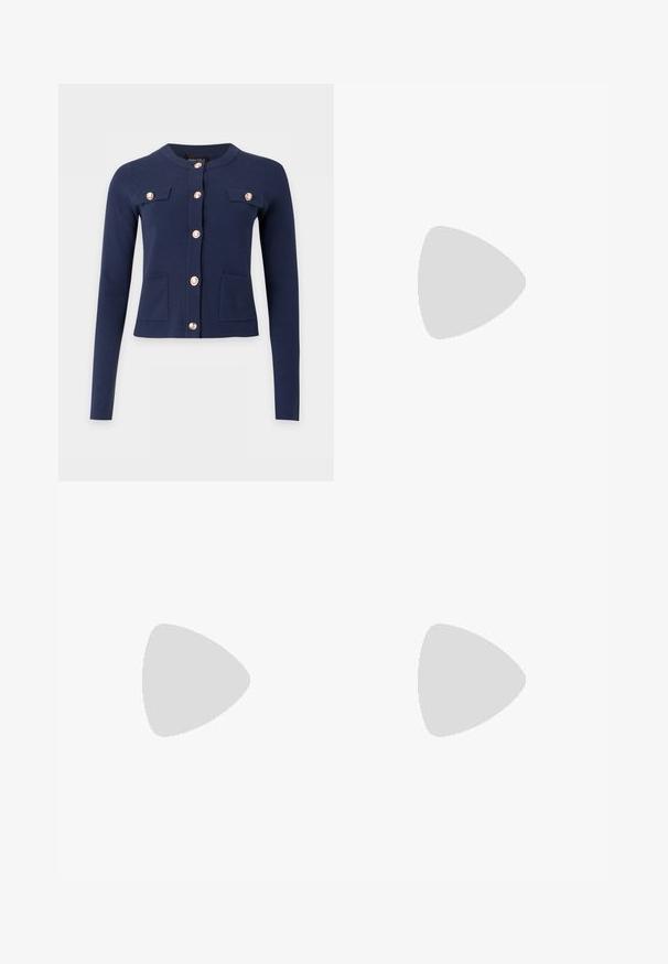 Cardigan bleu marine à manches longues avec col rond, boutons dorés sur le devant, deux poches poitrine à rabat et deux poches inférieures.; Deux t-shirts en coton blanc à manches courtes, à encolure ronde et à coupe ajustée, présentant une texture lisse et un design minimaliste.; Pantalon beige ajusté à jambe droite avec passants de ceinture, fermeture éclair frontale et bouton, sur un fond clair uni.; Baskets basses blanches avec lacets blancs et semelle en caoutchouc, vues de côté sur un fond neutre.