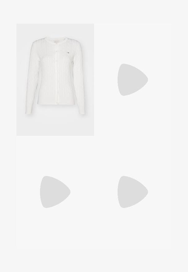 Cardigan blanc en maille torsadée à manches longues, boutonné, avec un col rond et un petit logo brodé sur la poitrine gauche.; T-shirt à manches longues bleu marine avec un col en V, fabriqué à partir d'un tissu doux avec une surface légèrement texturée et un ourlet arrondi.; TOM TAILOR STELLA denim bleu foncé; Mocassin en cuir marron foncé posé sur un tapis texturé bleu ondulé, avec un canapé gris doux flou en arrière-plan.