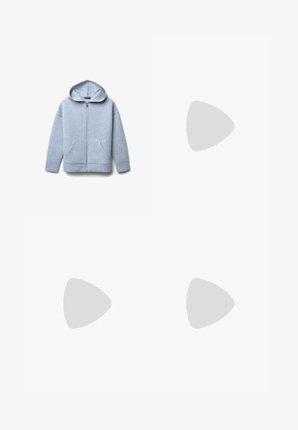 Hellgraue Zip-Hoodie aus weichem Material mit großer Kapuze, zwei vorderen Taschen sowie geripptem Saum und Bündchen.; Weißes T-Shirt mit schwarzen Raglanärmeln und "Guess Jeans" in hellem Pink quer über der Brust gedruckt.; Schwarze ausgestellte Hosen aus einem glatten, dehnbaren Stoff. Mit einem hohen Bund und ausgestellten Säumen für eine figurschmeichelnde Passform. Einfaches Design.; Blaue Wildleder-Sneaker mit weißen Streifen und strukturierten Mustern, kombiniert mit hellblauen Jeans, vor einem grünen Hintergrund.