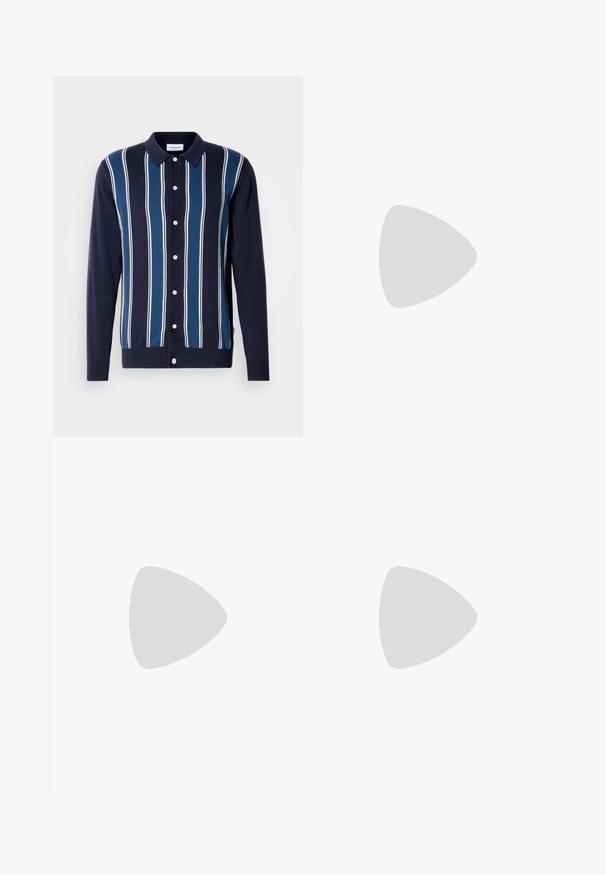 Polo de manga larga en azul marino con rayas alternas finas y gruesas en azul y blanco. Cuenta con un cierre de botones en la parte delantera y un cuello clásico.; Camiseta de algodón blanca con cuello redondo y mangas cortas. Presenta un pequeño detalle del logo en el frente. Textura suave y corte casual.; Vaqueros ajustados de color azul oscuro con detalles desgastados, diseño clásico de cinco bolsillos, cierre de botón y presillas para cinturón.; Mocasín de cuero marrón con detalle de borlas, descansando sobre una alfombra beige texturizada frente a un sofá de color arena claro.