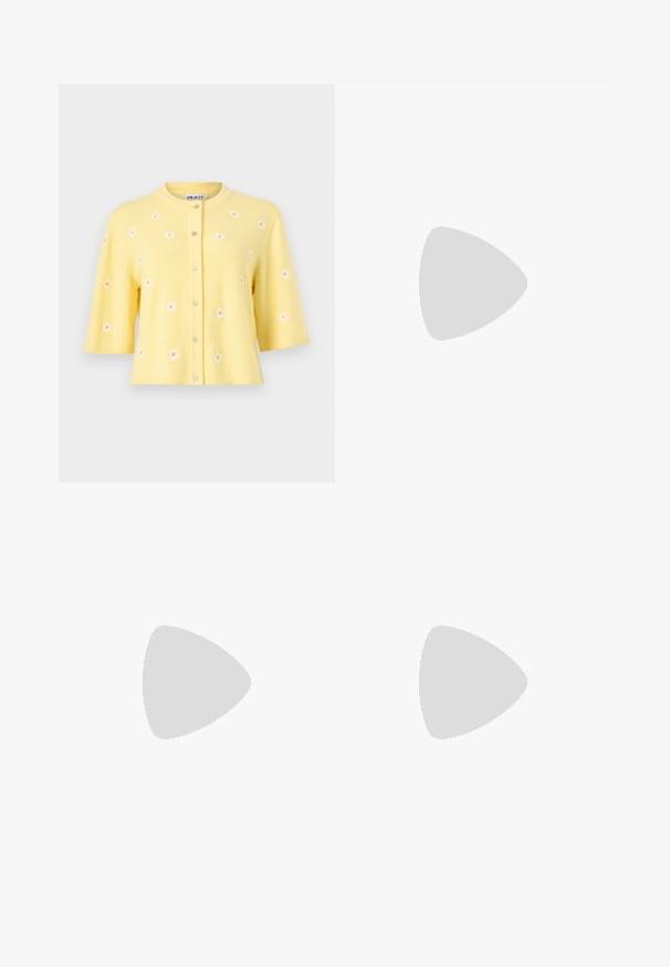 Cardigan jaune à manches courtes avec encolure ronde, boutons sur le devant et petits motifs de marguerites blanches éparpillés sur le tissu.; Body noir sans manches à col montant avec fines bretelles sur fond blanc.; Mini jupe en tricot blanc avec un motif texturé, une taille élastique et une silhouette droite.; Jambes portant des leggings côtelés foncés associés à des ballerines noires avec de petits détails en nœud sur fond blanc.