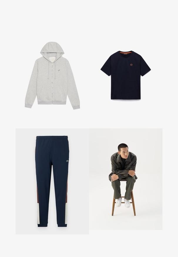 Grijze zip-up hoodie gemaakt van een zachte katoenen mix. Beschikt over een capuchon, zijzakken en een klein geborduurd logo op de borst.; Marineblauw T-shirt met korte mouwen, ronde hals en een klein rond logo op de linkerborst.; Marineblauwe trainingsbroek gemaakt van zacht materiaal, met bruine en crèmekleurige zijpanelen, een elastische tailleband en een klein logo op de voorkant.; Jonge man in een donkere leren jas en spijkerbroek zit op een houten kruk, leunt naar voren met gekruiste armen en kijkt naar de zijkant tegen een witte achtergrond.
