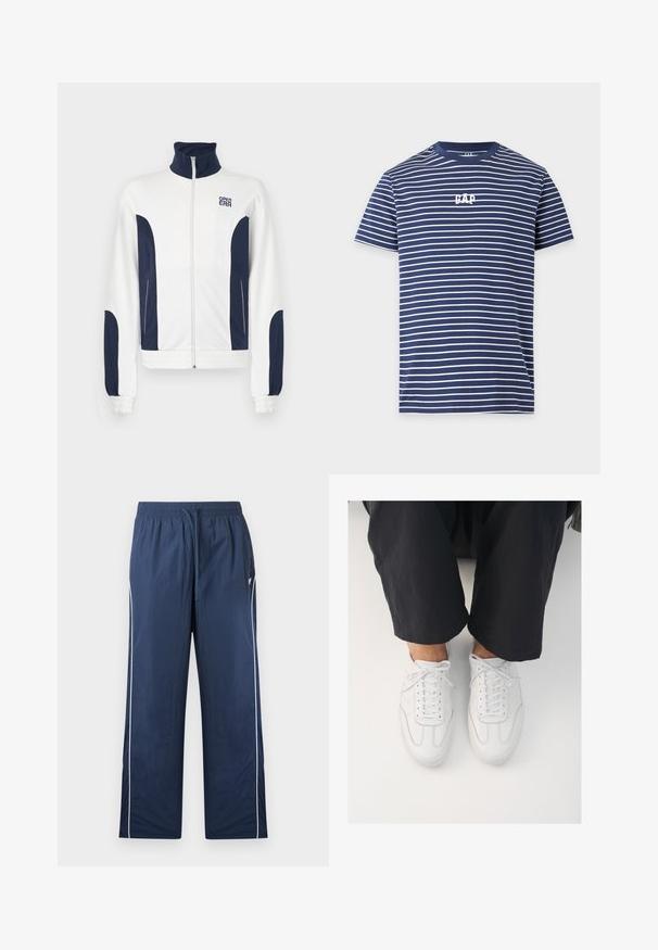 Witte zip-up jas met marineblauwe accenten aan de zijkanten en mouwen. Staande kraag, elastische manchetten en logo op de borst. Glad materiaal.; Marineblauw T-shirt met korte mouwen, dunne witte horizontale strepen en wit "GAP" logo gecentreerd op de borst.; Marineblauwe trainingsbroek met elastische tailleband, trekkoord, witte zijstrepen en een klein logo aan de bovenkant van de linkerkant.; Witte leren sneakers met een gladde textuur, ronde neus en klassiek vetersysteem, gepositioneerd boven donkere, losse broeken.