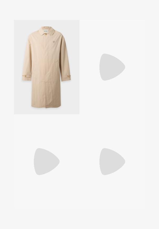 Long manteau beige avec poignets boutonnés, un seul bouton supérieur visible, deux poches latérales et un petit logo brodé sur la poitrine gauche.; Polo bleu marine à manches courtes avec patte à deux boutons, col et poignets rayés, et petit logo laurier jaune sur la poitrine.; Jean en denim bleu foncé, coupe droite, avec fermeture par bouton, poches avant et arrière, et détails de coutures visibles.; Chaussure bateau en cuir brun foncé avec semelle marron clair et détails en lacets, vue en angle au-dessus d'un sol gris avec des rideaux blancs en arrière-plan.