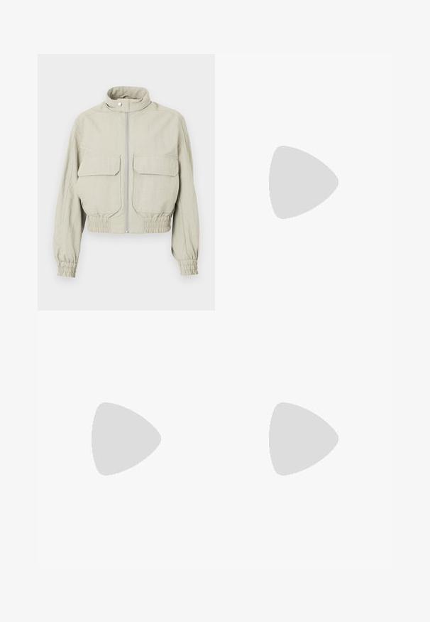 Veste cropped gris clair avec un col montant, fermeture éclair devant et deux grandes poches poitrine. Les poignets et l'ourlet élastiqués ajoutent de la texture.; T-shirt en coton bleu marine avec une coupe décontractée. Il présente un design graphique avec "TIMBS Authentic" dans des couleurs contrastées. Manches courtes, col rond.; Shorts en lin beige avec deux poches latérales, une fermeture à bouton à l'avant, coupe droite et texture lisse. Design épuré sans motifs.; Baskets blanches Adidas Samba avec des bandes noires et une semelle en gomme, flottant au-dessus de marches en béton gris texturé.