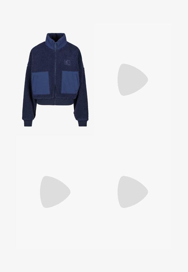 Veste cropped bleu marine en polaire douce et texturée, avec un col montant, une fermeture éclair et deux poches plaquées en tissu contrastant.; Pull en tricot gris clair avec des manches longues, un col rond large et des poignets et un ourlet côtelés. Fabriqué en tissu doux et texturé.; Jean large bleu foncé en denim avec fermeture à bouton et à glissière, cinq poches et coutures jaunes.; Bottine en daim marron avec doublure en fourrure claire, semelle plate en caoutchouc et languette au talon, conçue pour le confort par temps froid.