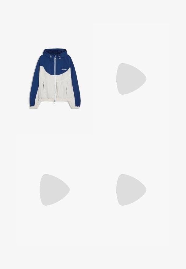 Blå og beige vindjakke med hætte og lynlås, elastiske manchetter og to lynlåslommer foran, med lille hvidt logo på brystet.; Lysegrå pullover hoodie med lange ærmer, for lomme foran og ribkant ved ærmerne på hvid baggrund.; Grå sweatpants lavet af blødt stof med snor i taljen, tætsiddende ben og en sidelomme med lynlås til sikker opbevaring.; Hvid lavtop sneaker med tyk sål, snørebånd foran og små ventilationshuller på siden, vist i profil.