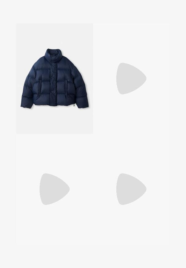 Doudoune bleu marine avec col montant, boutons-pression à l'avant, matelassage horizontal et deux poches avant, présentée sur fond blanc.; Chemise blanche à manches longues avec fines rayures verticales noires, col pointu, poche poitrine et poignets boutonnés.; Pantalon beige pour homme, tailleur, avec de fines rayures verticales, passants pour ceinture et fermeture à glissière à l'avant.; Baskets basses blanches avec semelles découpées uniques portées avec un pantalon clair sur un sol en bois.