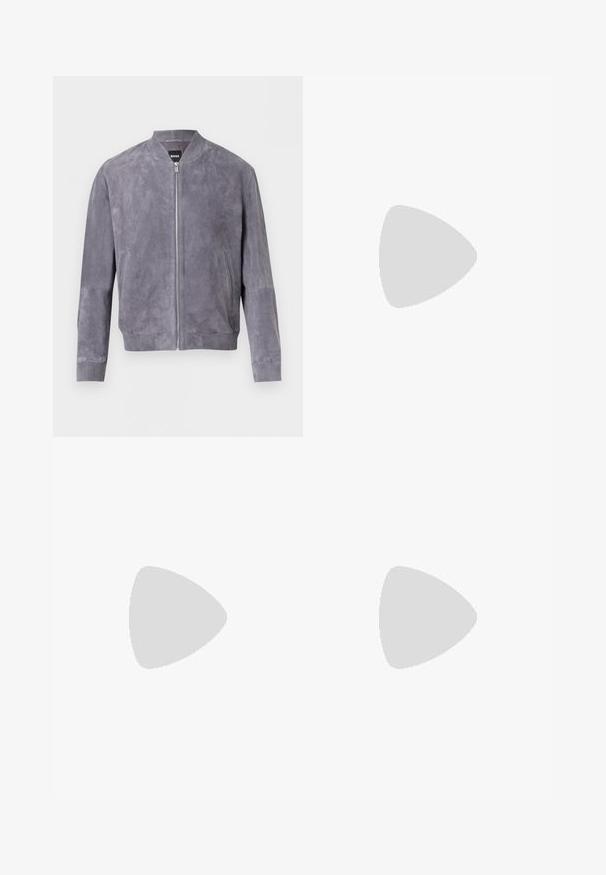 Blouson aviateur en daim gris avec fermeture éclair frontale, col, poignets et ceinture côtelés, doté de poches latérales et d'une étiquette BOSS à l'intérieur du col.; T-shirt bleu clair à manches courtes et col rond avec logo "BOSS" embossé sur la poitrine et une petite étiquette noire "BOSS" au niveau du col.; Jean denim bleu clair avec une ceinture bleu foncé, coupe droite, cinq poches et détails de couture visibles.; Mocassin noir en cuir à enfiler avec semelle beige, positionné en suspension près d'un porte-revues en fil métallique sur un sol en terrazzo.