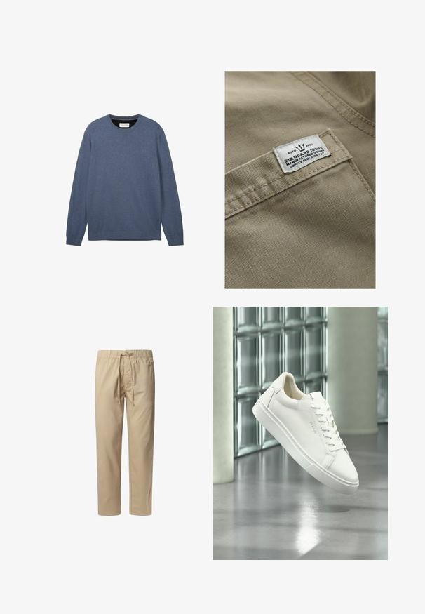 Khaki stof med en struktureret overflade, der har et hvidt mærke syet på en lomme – teksten inkluderer "ESTD 1982," "STANDARD ISSUE" og forsyningsreference.; Crewneck sweater i mørkeblå, fremstillet af blødt stof med en glat tekstur, der har lange ærmer og ribbede manchetter samt kant.; Beige, lette bukser med elastisk talje og justerbar snøre, som har to sidelommer og lige ben.; Hvid lav top sneaker med snørebånd, der svæver over en reflekterende betongulv mod en glasblokvæg baggrund.