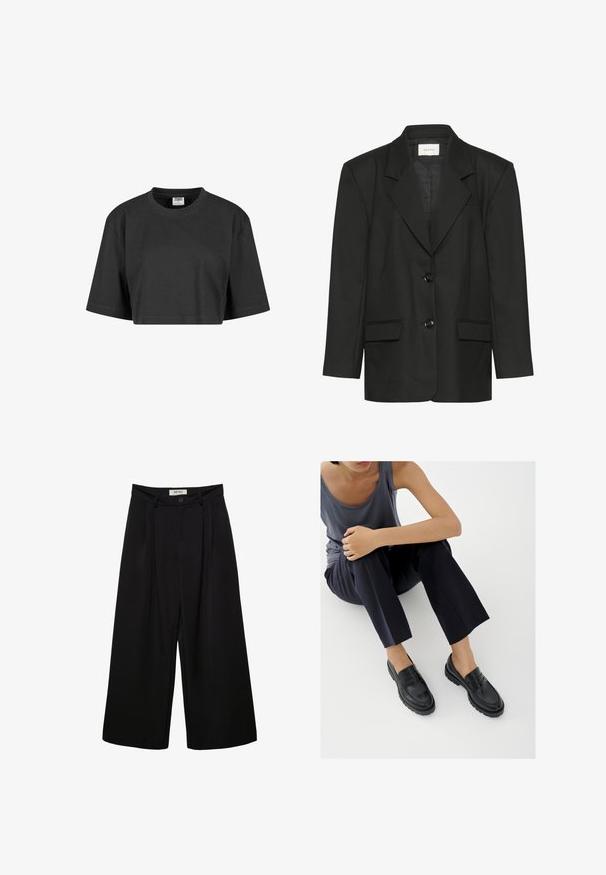 Sort blazer med skræddersyet pasform, spidse revers, to knapper og to forlommer, lavet af et glat, struktureret stof.; Afskåret sort t-shirt lavet af bomuld, med en afslappet pasform, korte ærmer og en ribbet rund halsudskæring. Ingen synlige mønstre eller accenter.; Sorte bukser med vide ben og høj talje, med forreste læg, to sidelommer og knaplukning. Glat stoftekstur.; Sorte læderloafers med teksturerede detaljer, lav hæl, rund tå og synlige syninger. Modellen bærer mørke bukser og en grå top.